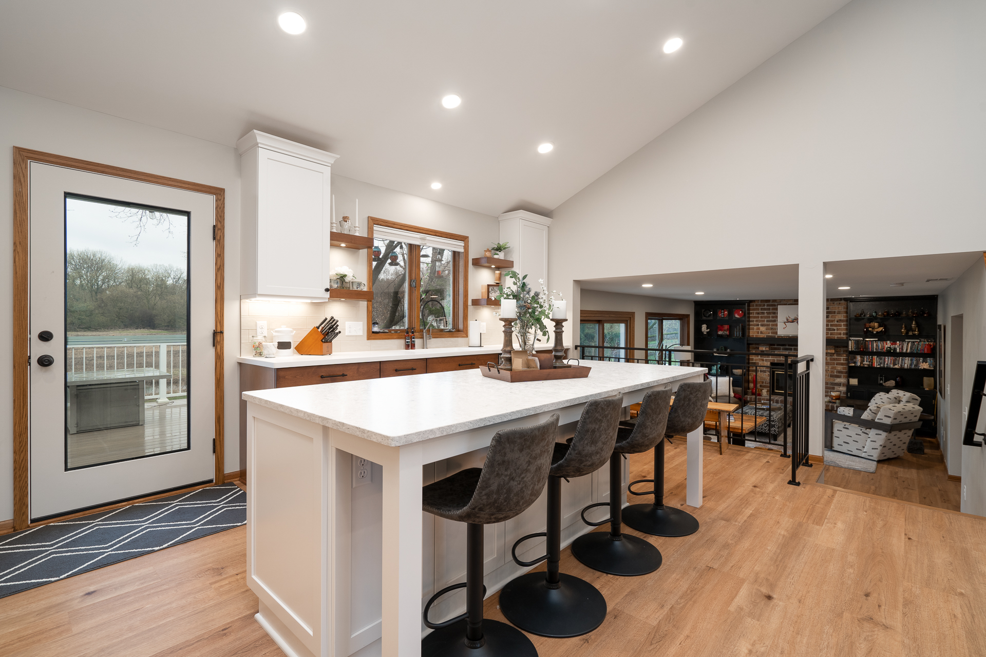 A bright and modern kitchen featuring an island and stylish bar stools with a view of the outdoors.
