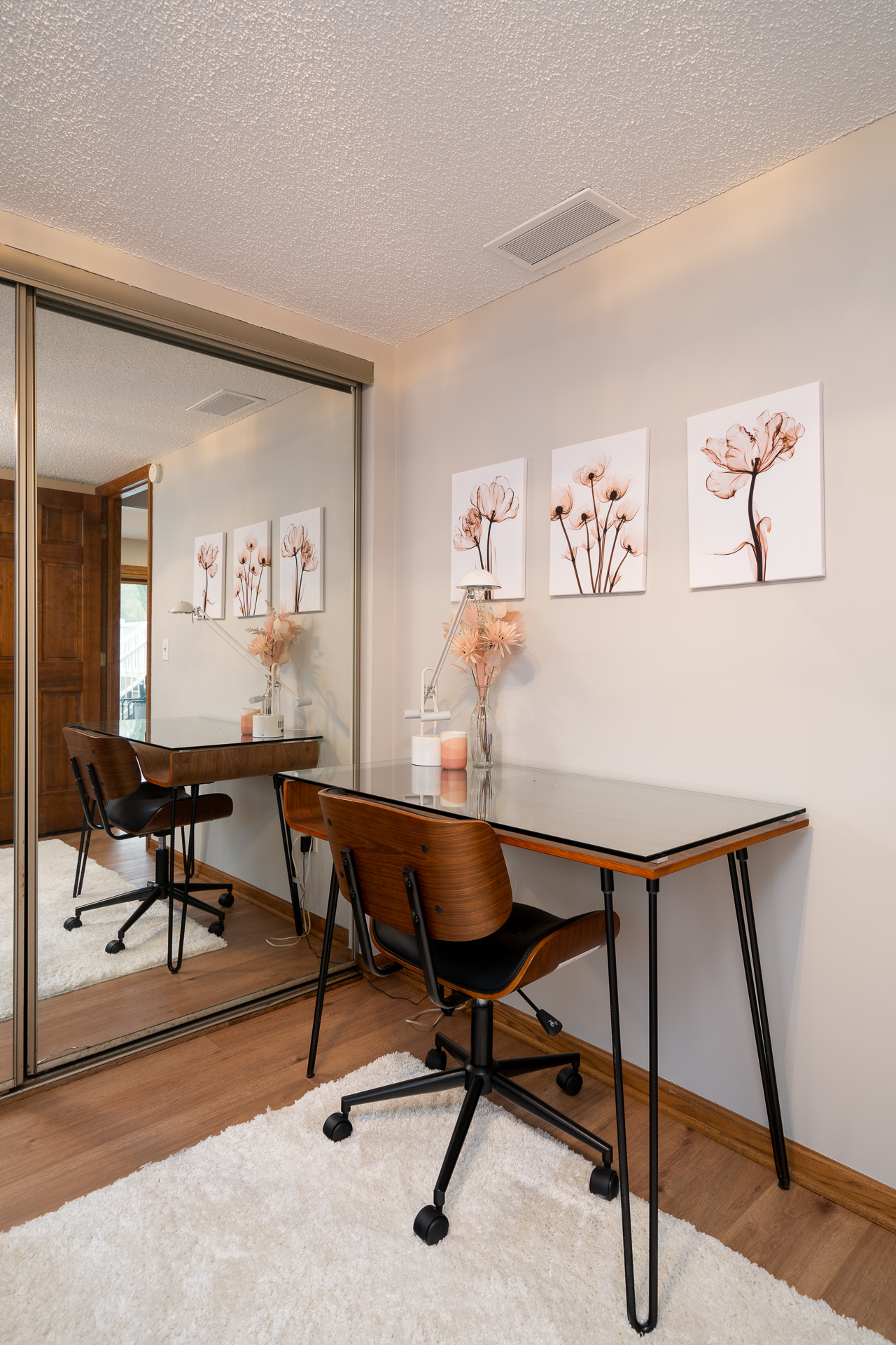A modern workspace featuring a glass desk, elegant décor, and botanical prints.