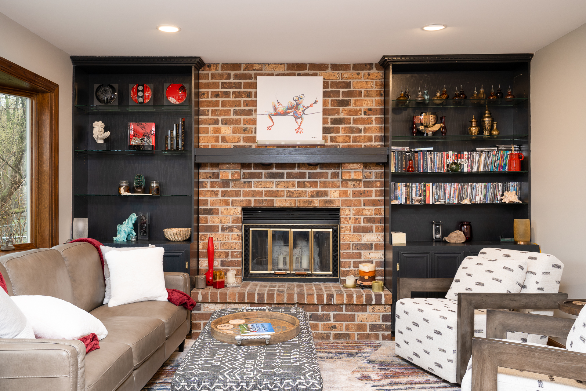 A cozy living room with a brick fireplace and decorative shelves.