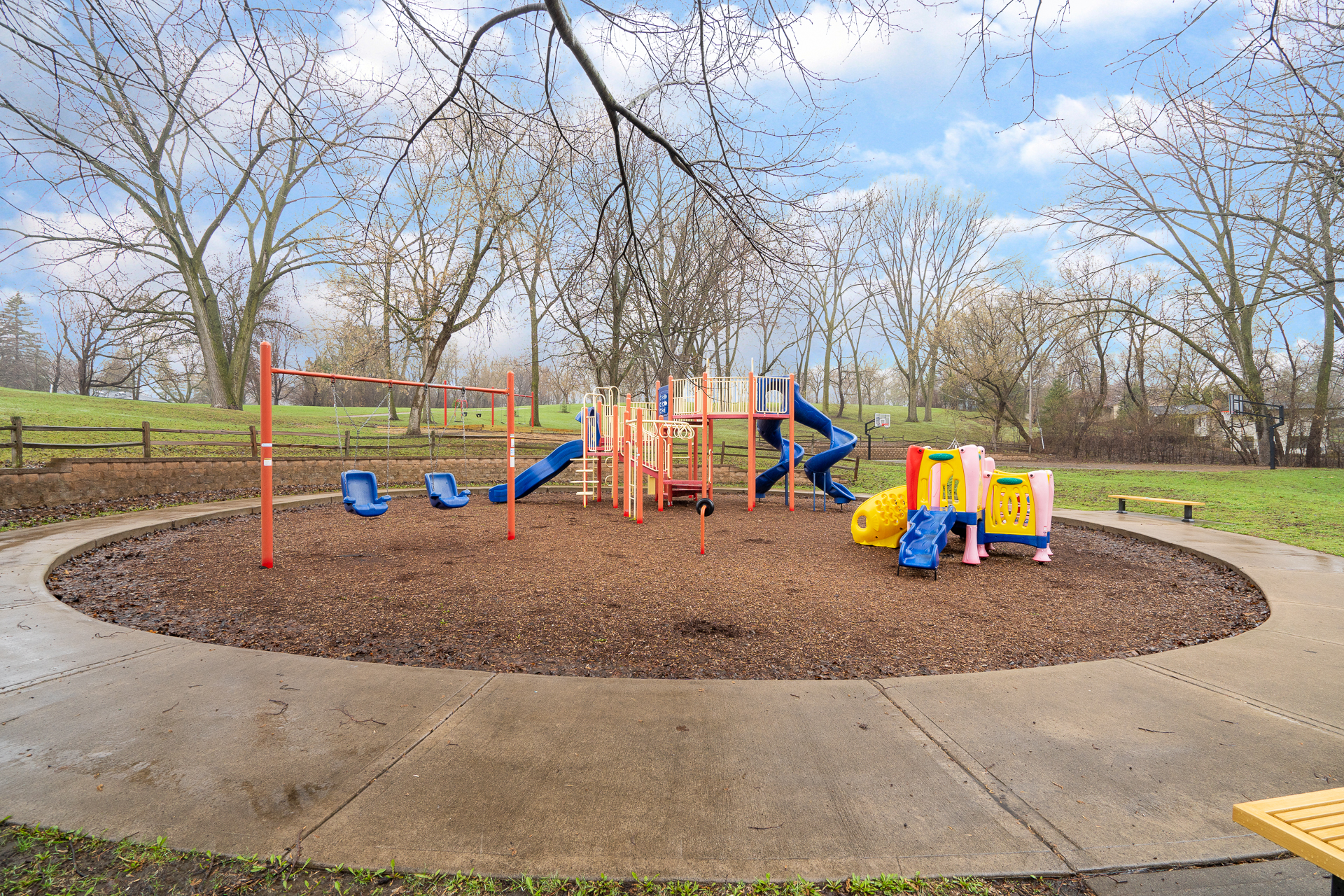 A colorful playground surrounded by trees in a park setting.