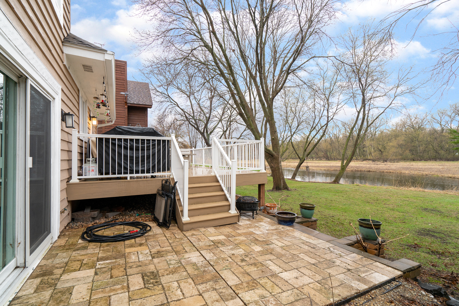 A tranquil backyard view featuring a deck, patio, and waterway.