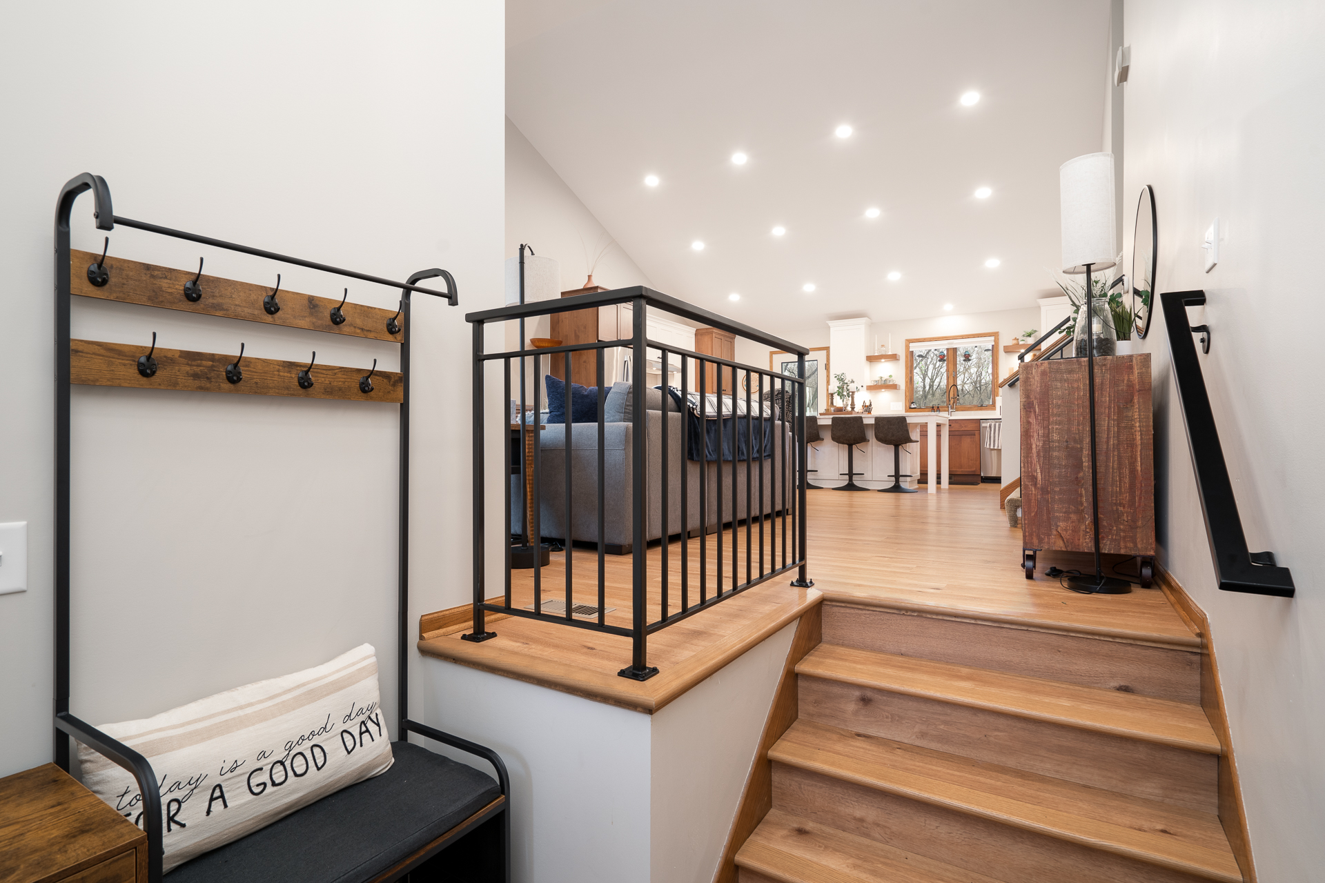 Inviting entryway with stylish coat rack and warm wooden staircase.