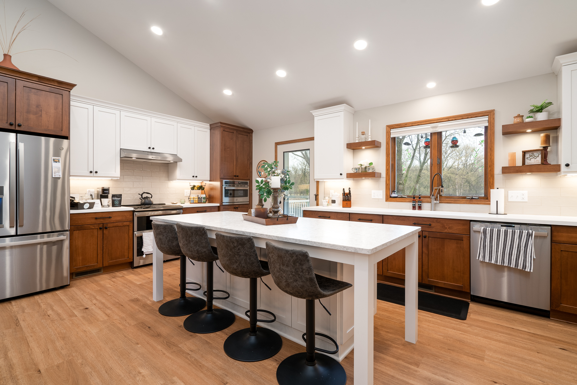 Modern kitchen with white and wood cabinetry, stainless steel appliances, and a central island.