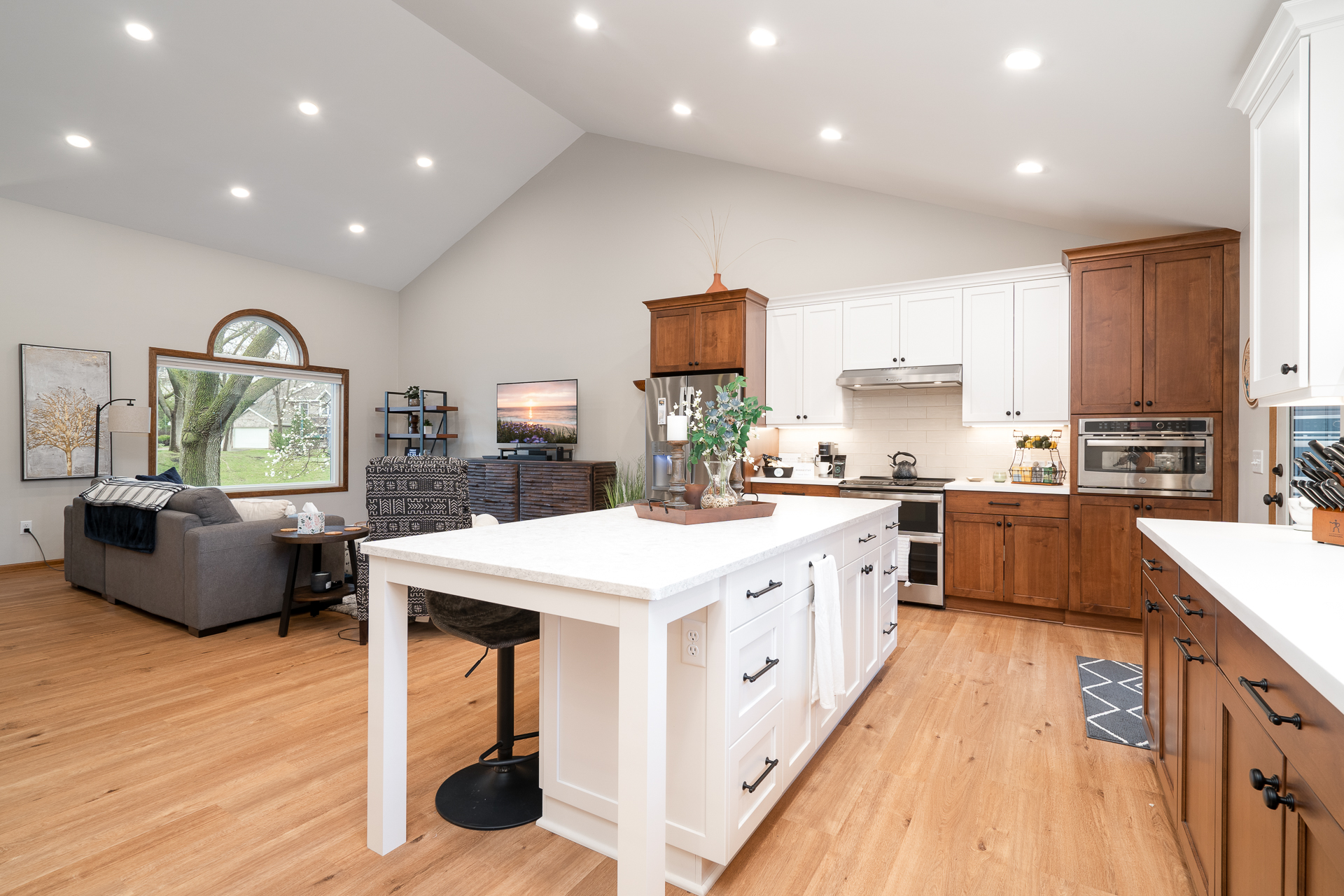 A modern open-concept kitchen and living area featuring a beautifully designed white and wooden kitchen with ample natural light.