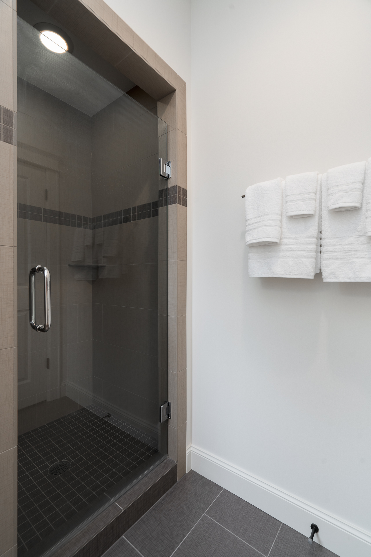 A modern shower space featuring a sleek glass door and neatly arranged towels.