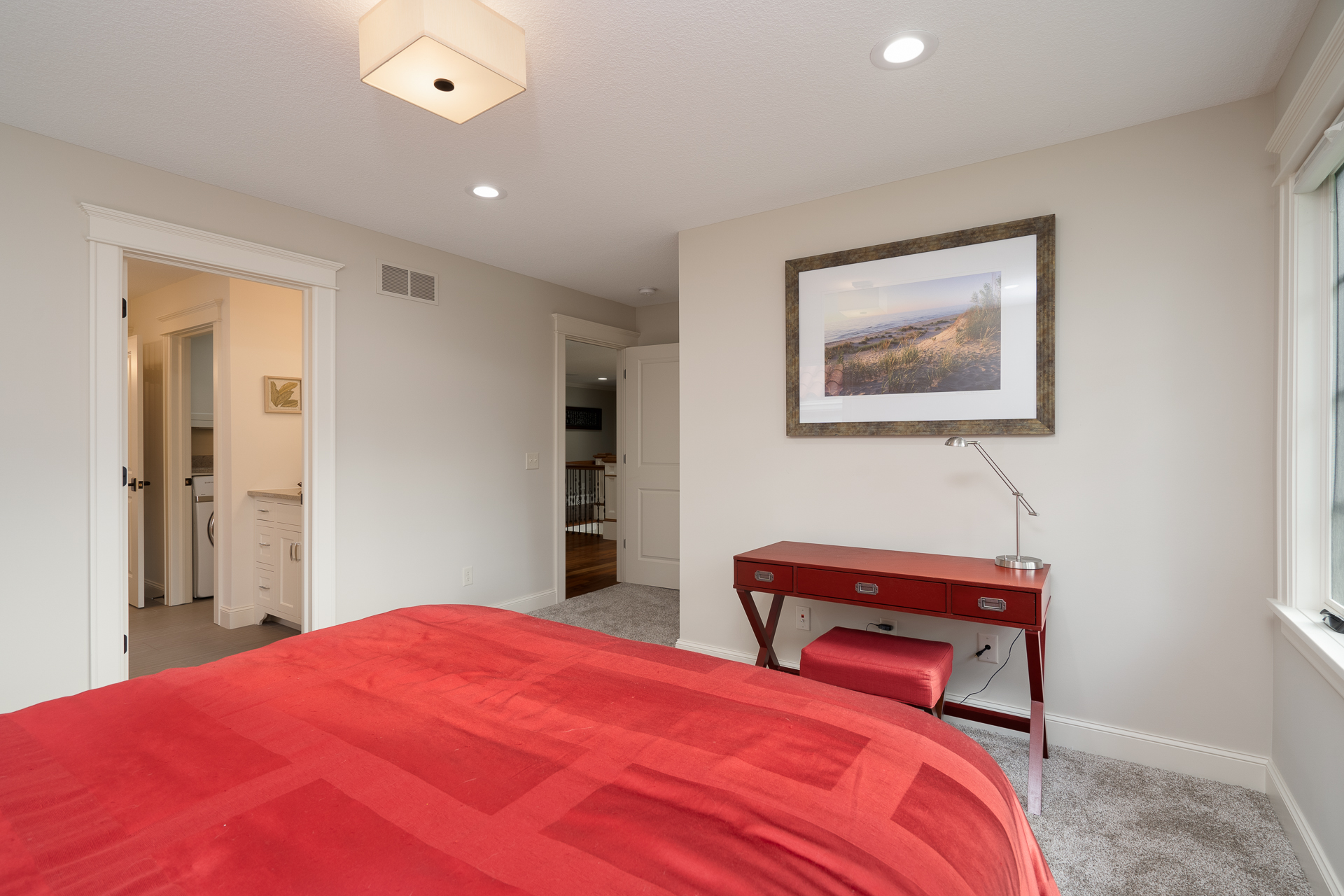 A modern bedroom with a vibrant red bedspread and stylish decor.