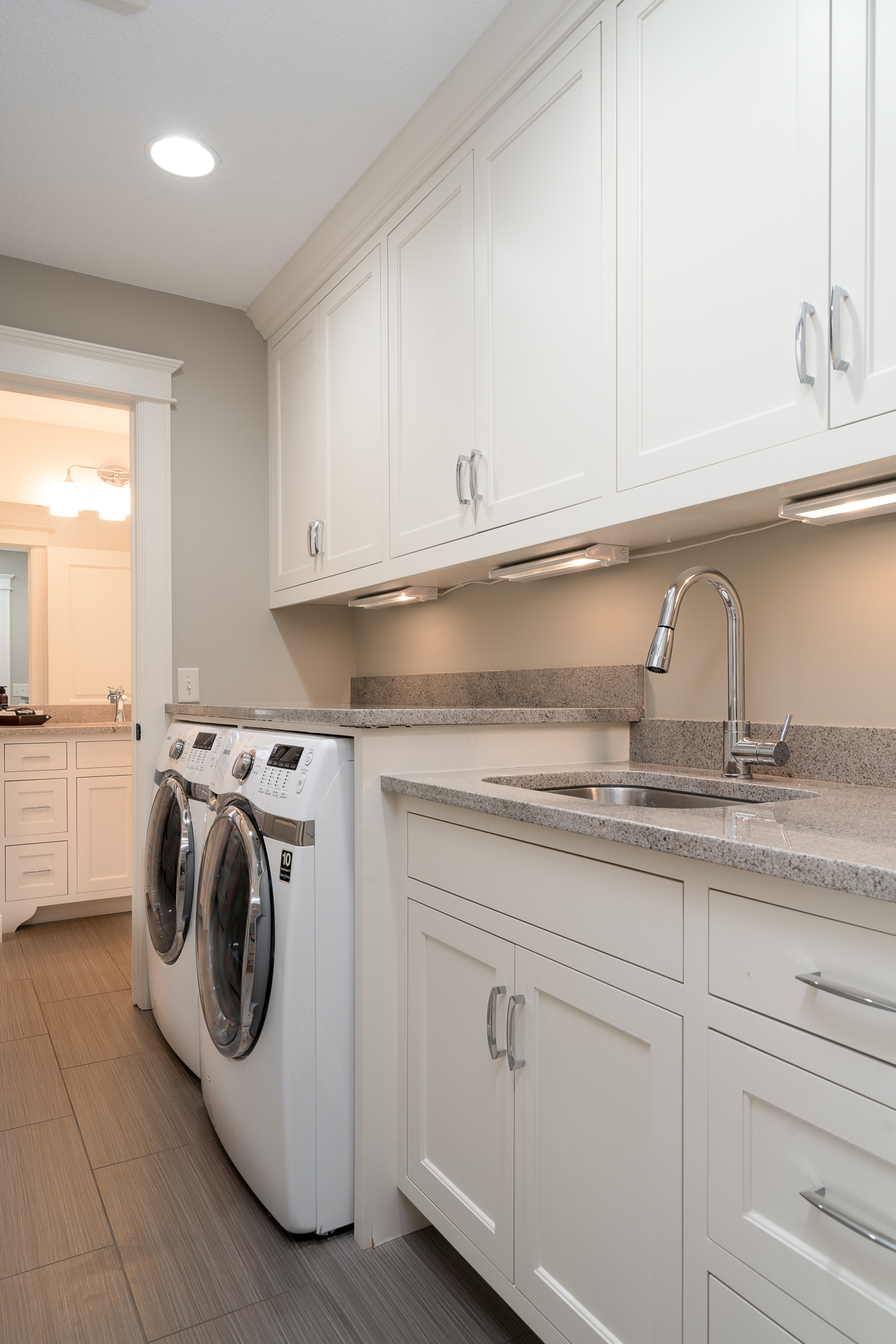 A tidy and modern laundry room with white cabinetry and sleek countertops.