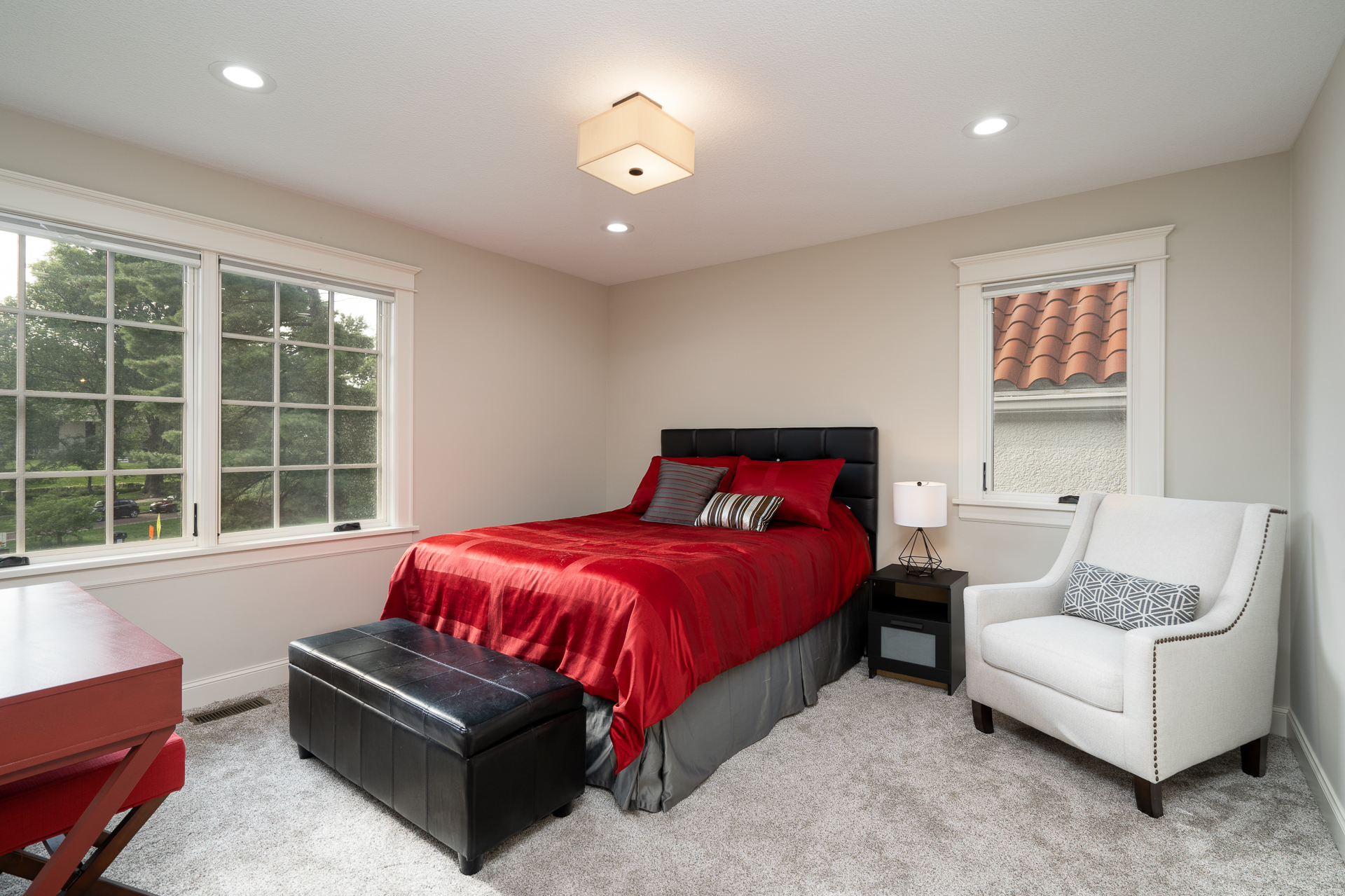 A modern, cozy bedroom with a vibrant red bedspread and stylish furnishings.