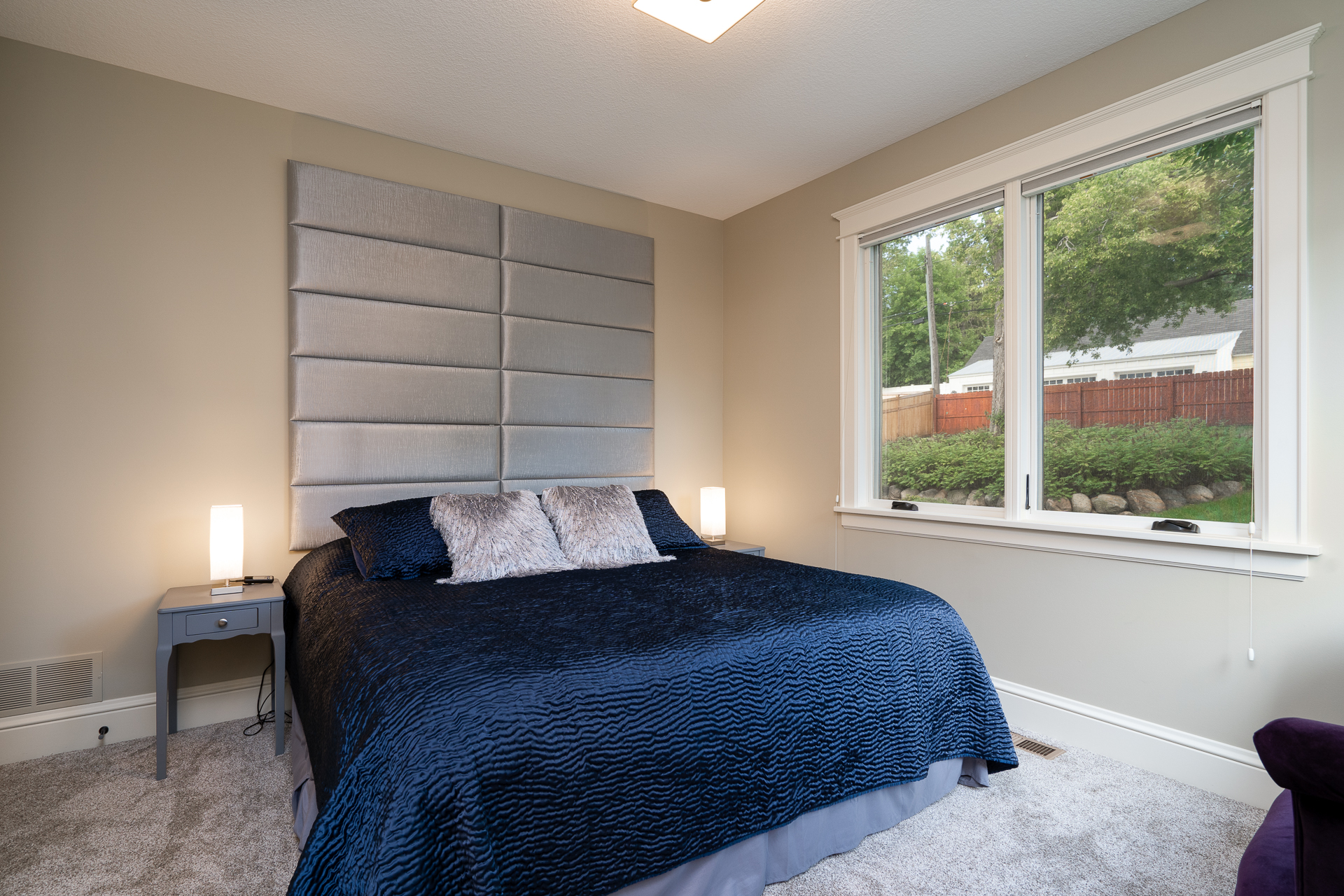 A modern bedroom with a navy blue bedspread and sleek decor.