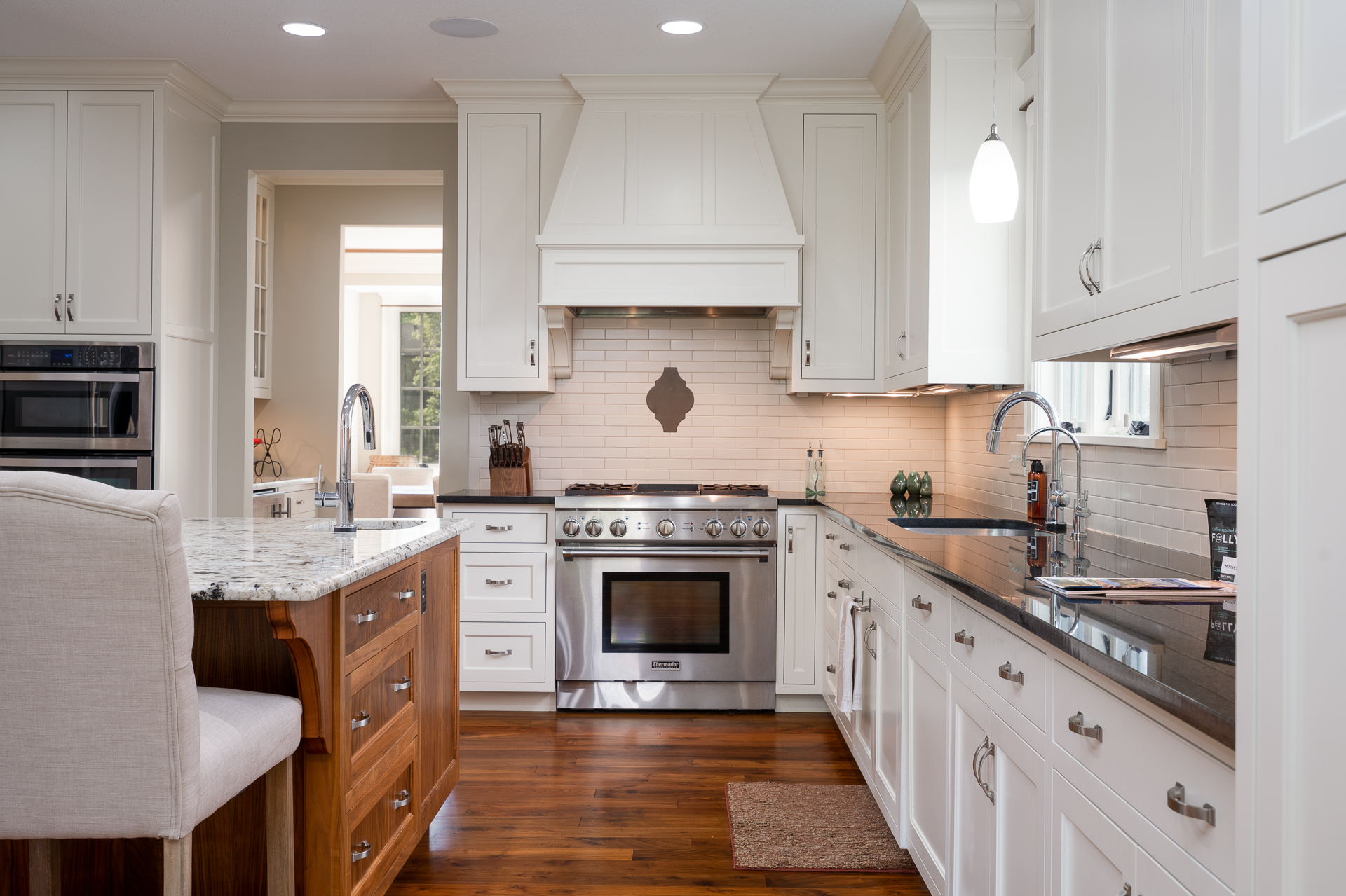 A modern kitchen featuring white cabinetry and dark granite countertops.