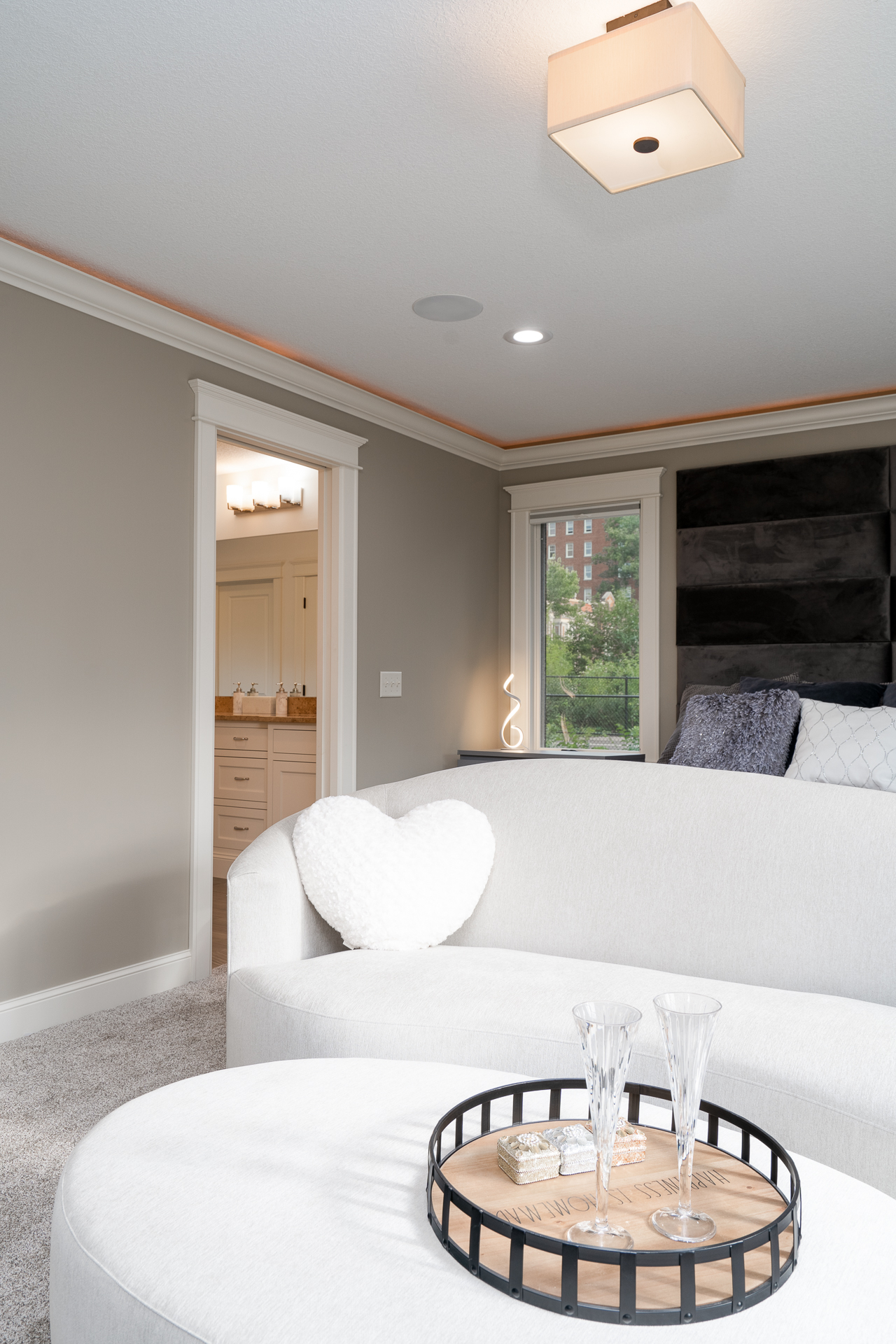 A modern living room with elegant decor including a heart-shaped pillow and crystal flutes.