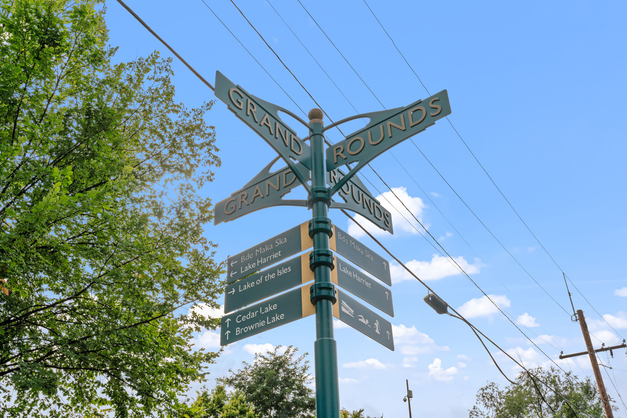 Directional signpost for the Grand Rounds, surrounded by greenery and blue skies.