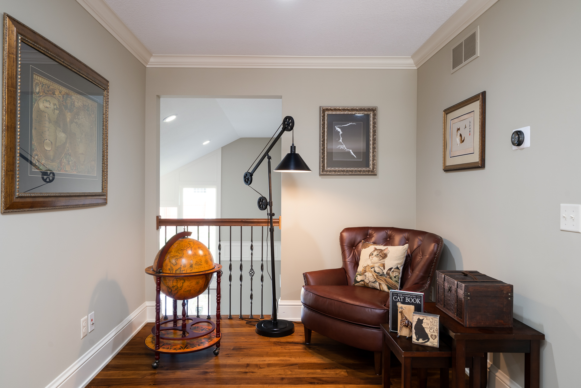 A cozy reading nook featuring a leather armchair, globe, and artistic decor.