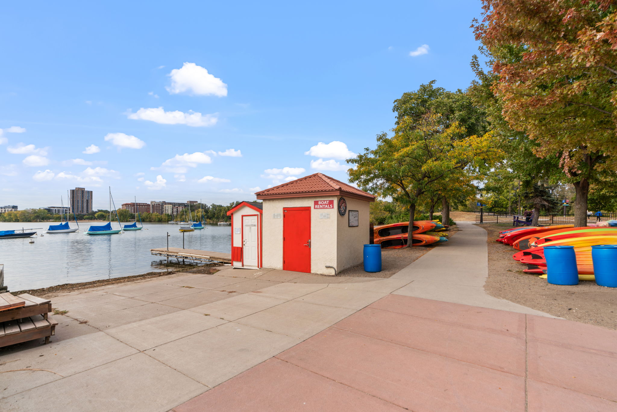 A charming lakeside scene featuring a boat rental shack and colorful kayaks.