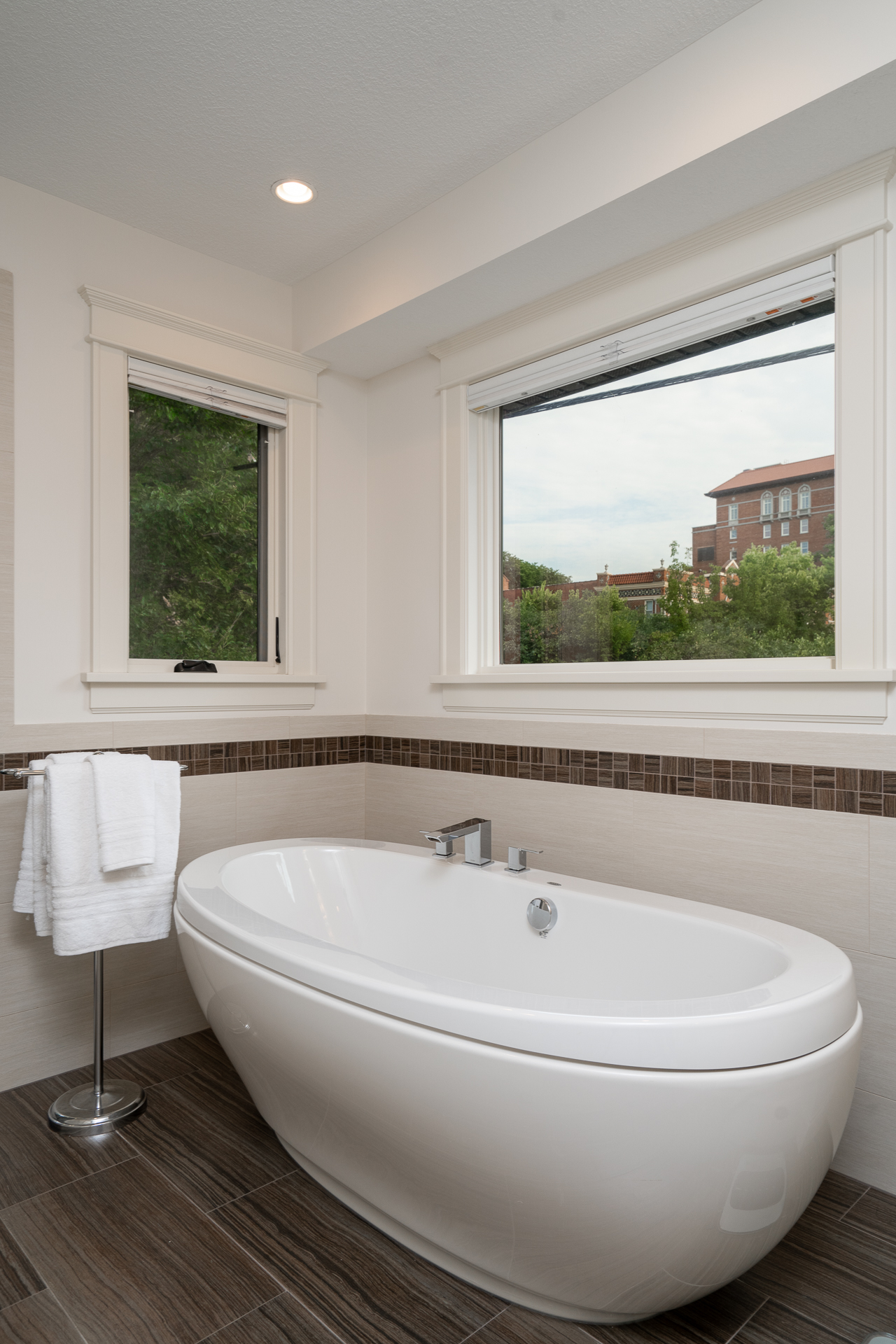 A modern bathroom featuring a luxurious freestanding bathtub and windows with a view.