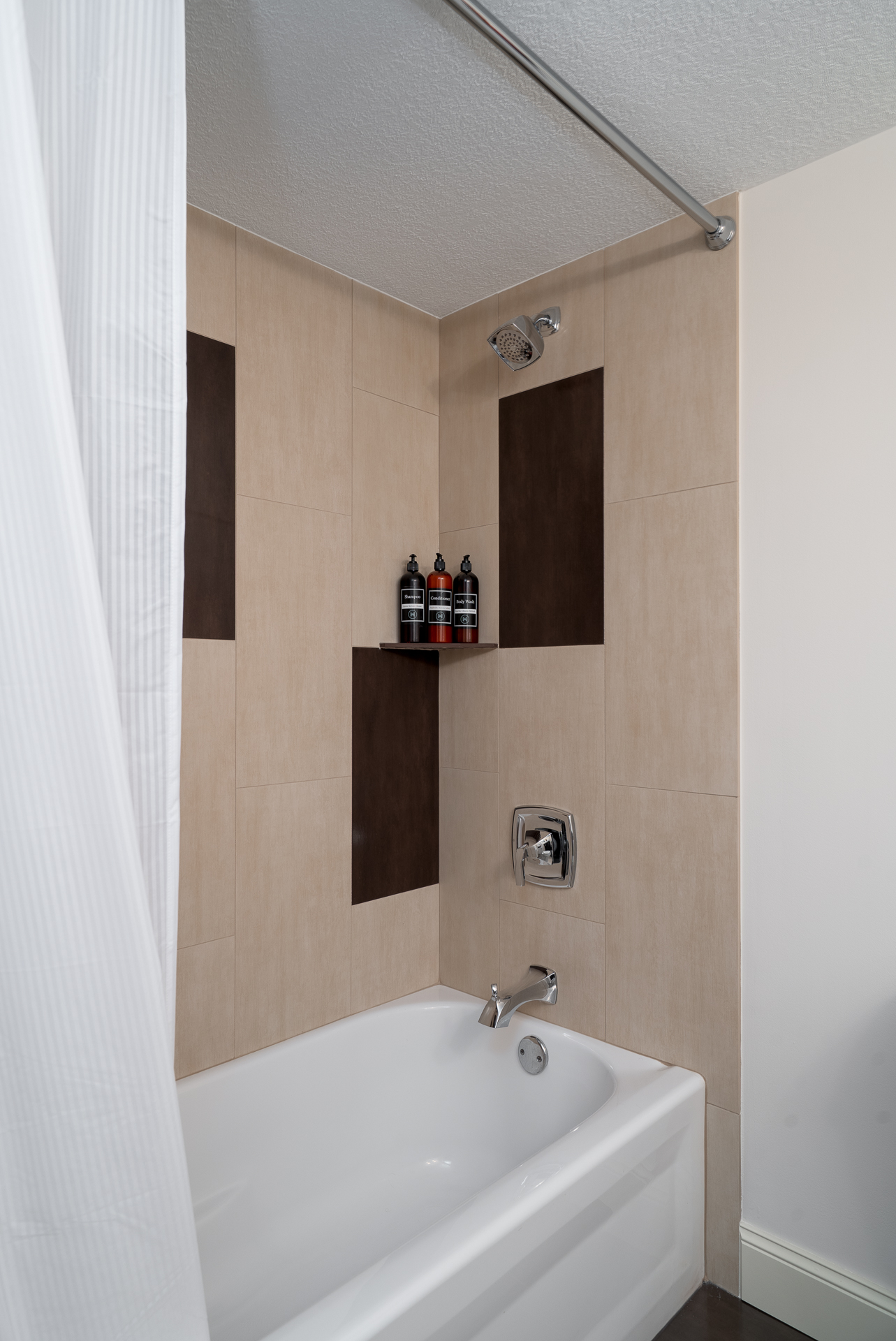A modern bathroom featuring a sleek shower and bathtub combination with organized toiletries.