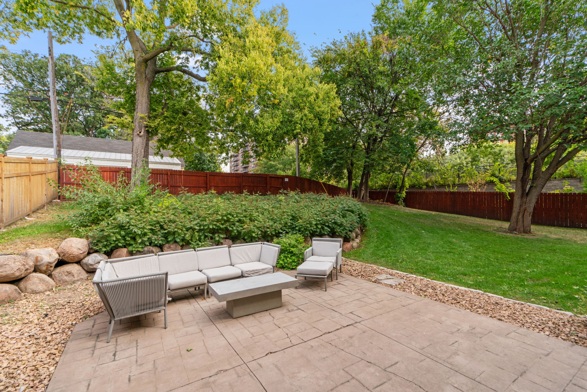 A cozy backyard patio area with modern seating and lush greenery.