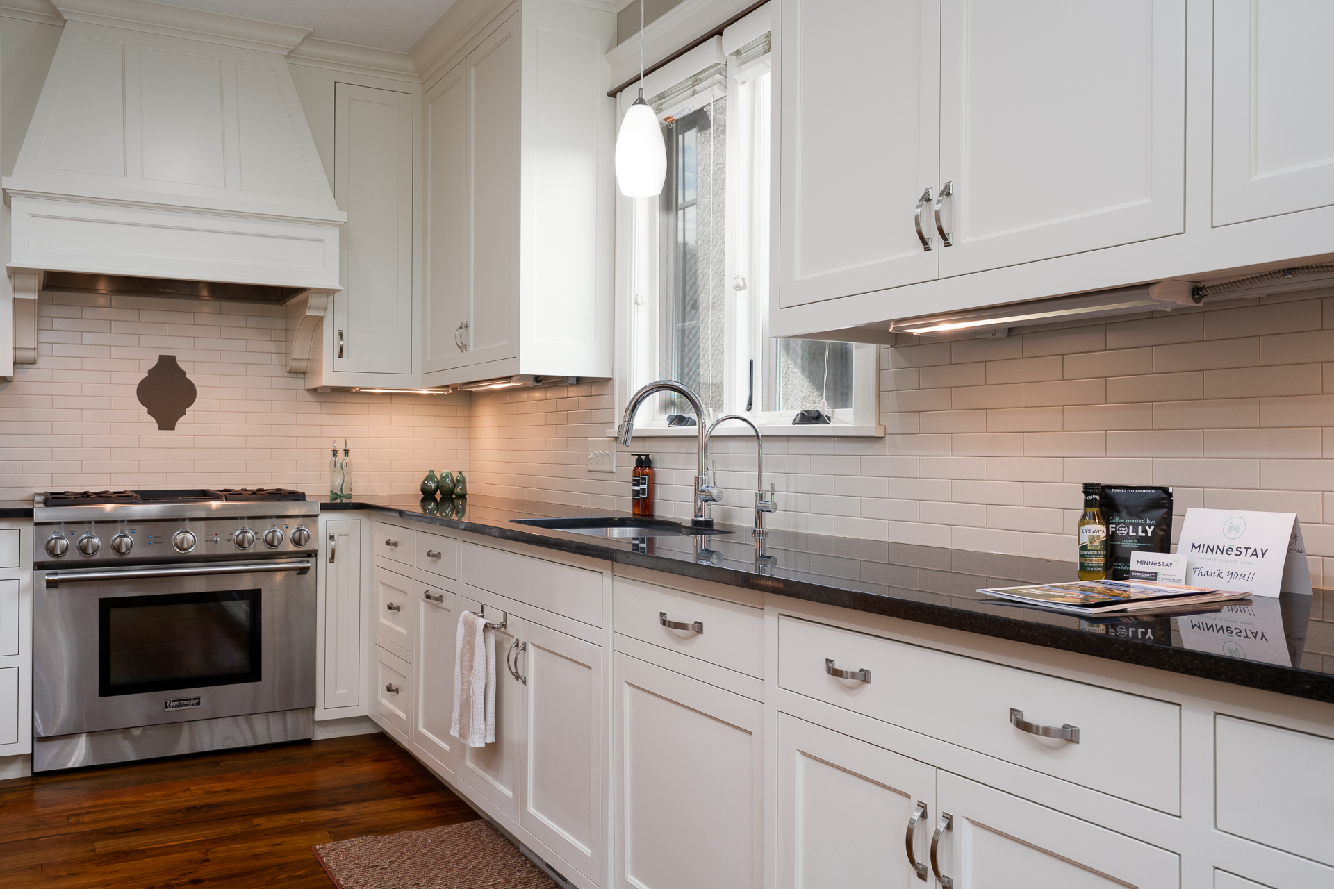 A modern kitchen featuring white cabinetry and dark granite countertops.