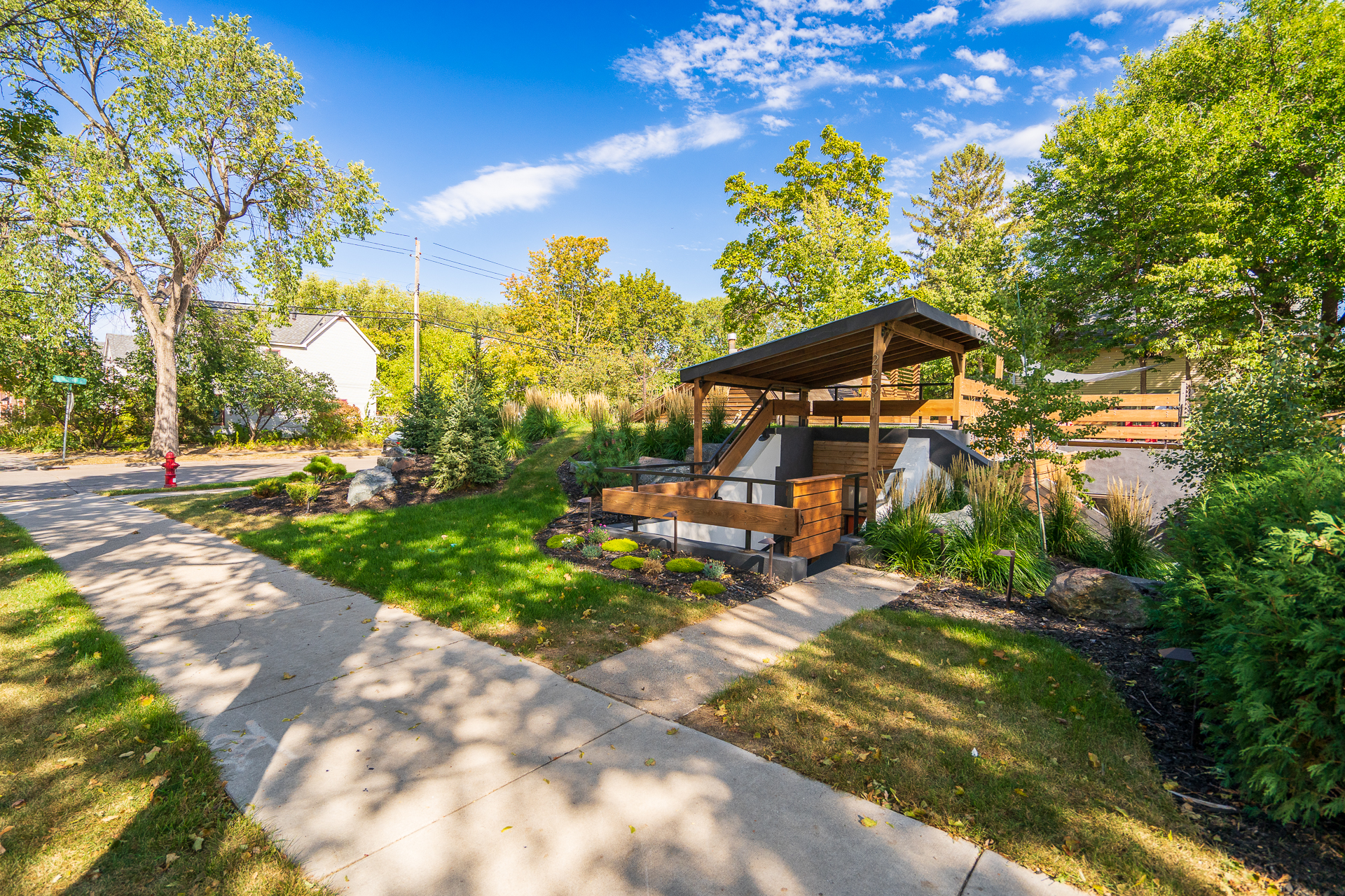 A modern gazebo nestled in a lush neighborhood, surrounded by greenery.