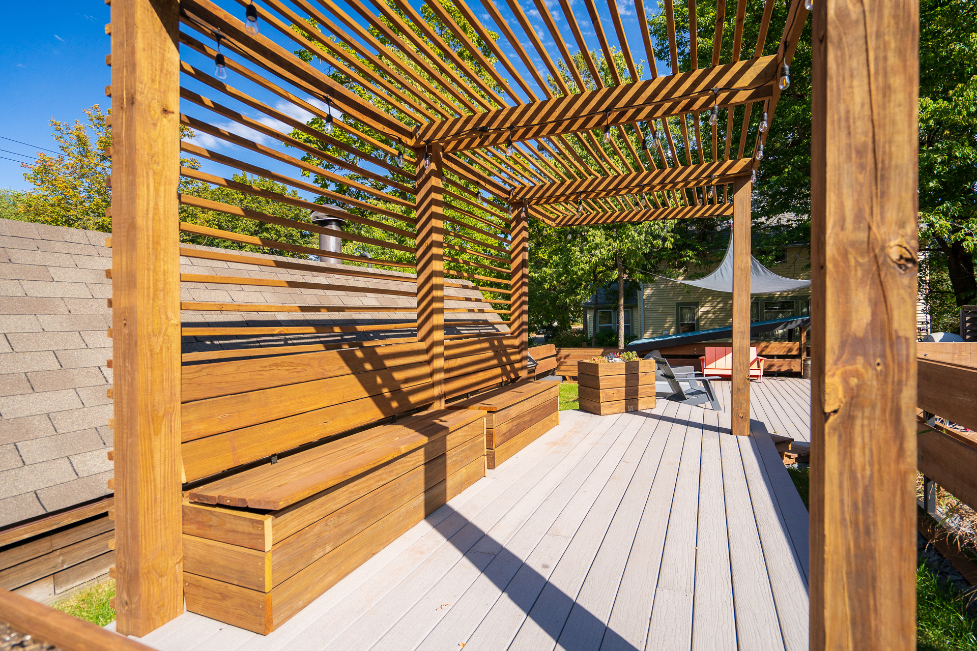 A modern wooden patio with slatted overhead structure and cozy seating.