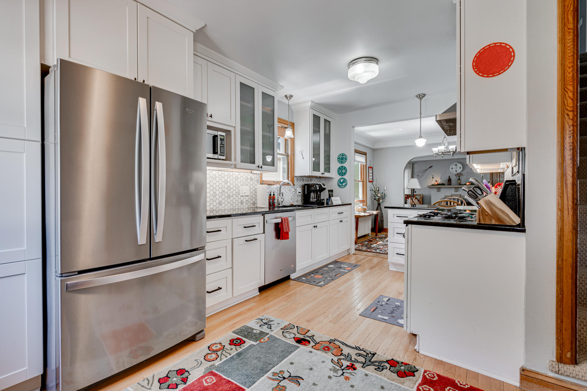 A modern kitchen with bright cabinetry and stylish stainless steel appliances, featuring a cozy dining area in the background.