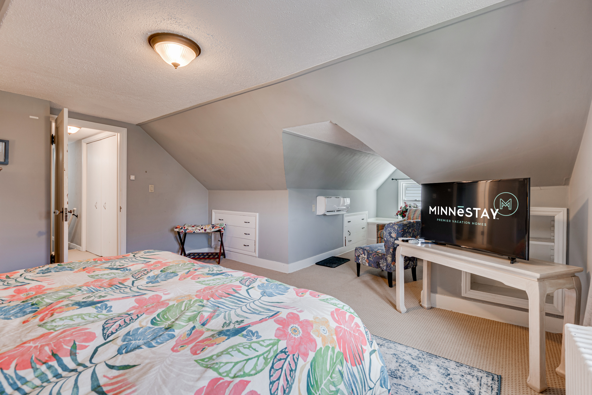 Cozy attic bedroom with floral decor and modern amenities.