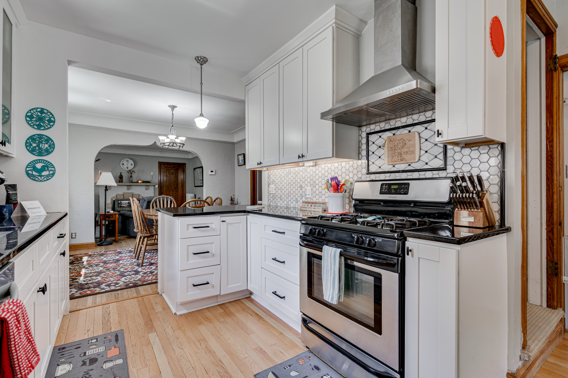 A modern kitchen featuring white cabinets, black countertops, and a stainless steel stove.