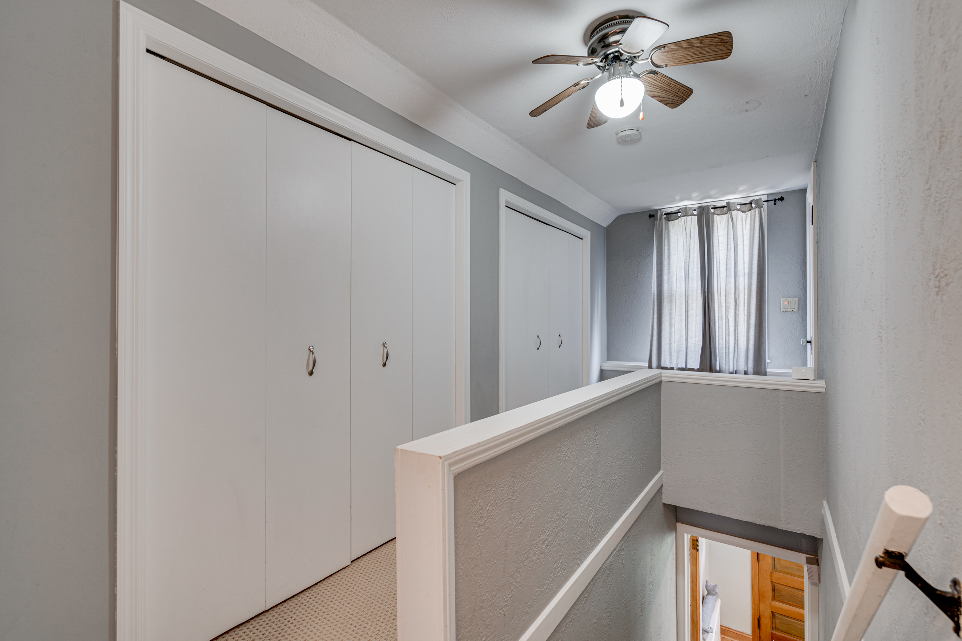 Bright and airy upstairs hallway with gray walls and white closets.
