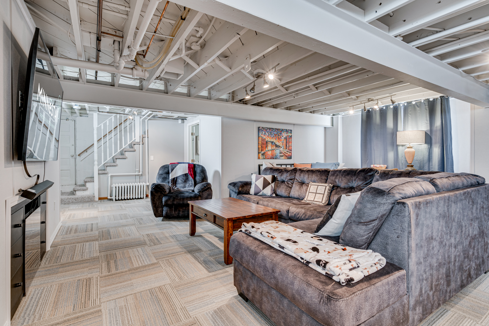 A modern and cozy basement living room with plush seating and decorative elements.