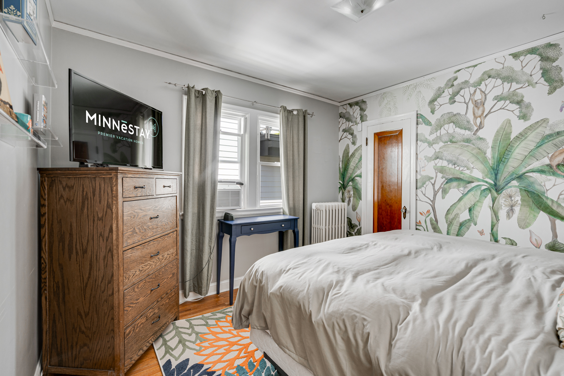 A cozy bedroom featuring tropical-themed wallpaper and modern decor.