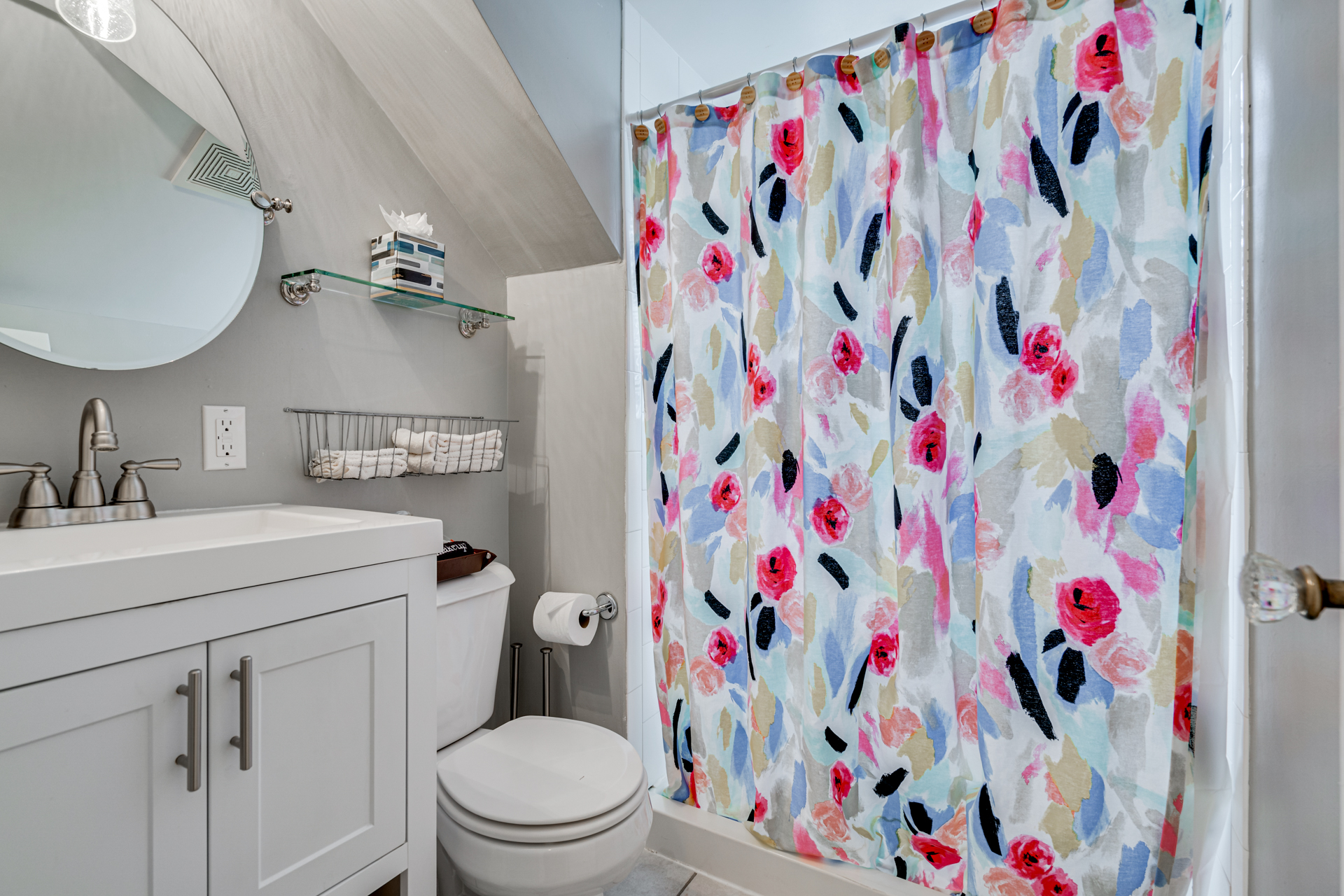 A bright and vibrant bathroom featuring a floral shower curtain and modern fixtures.