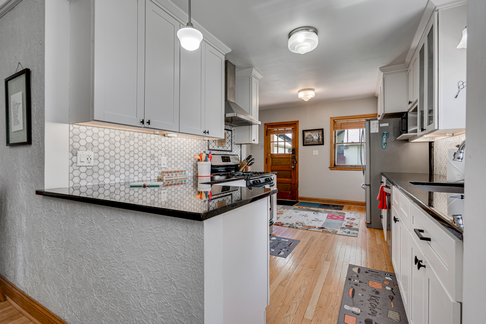 A modern kitchen with bright white cabinets and a cozy entrance.