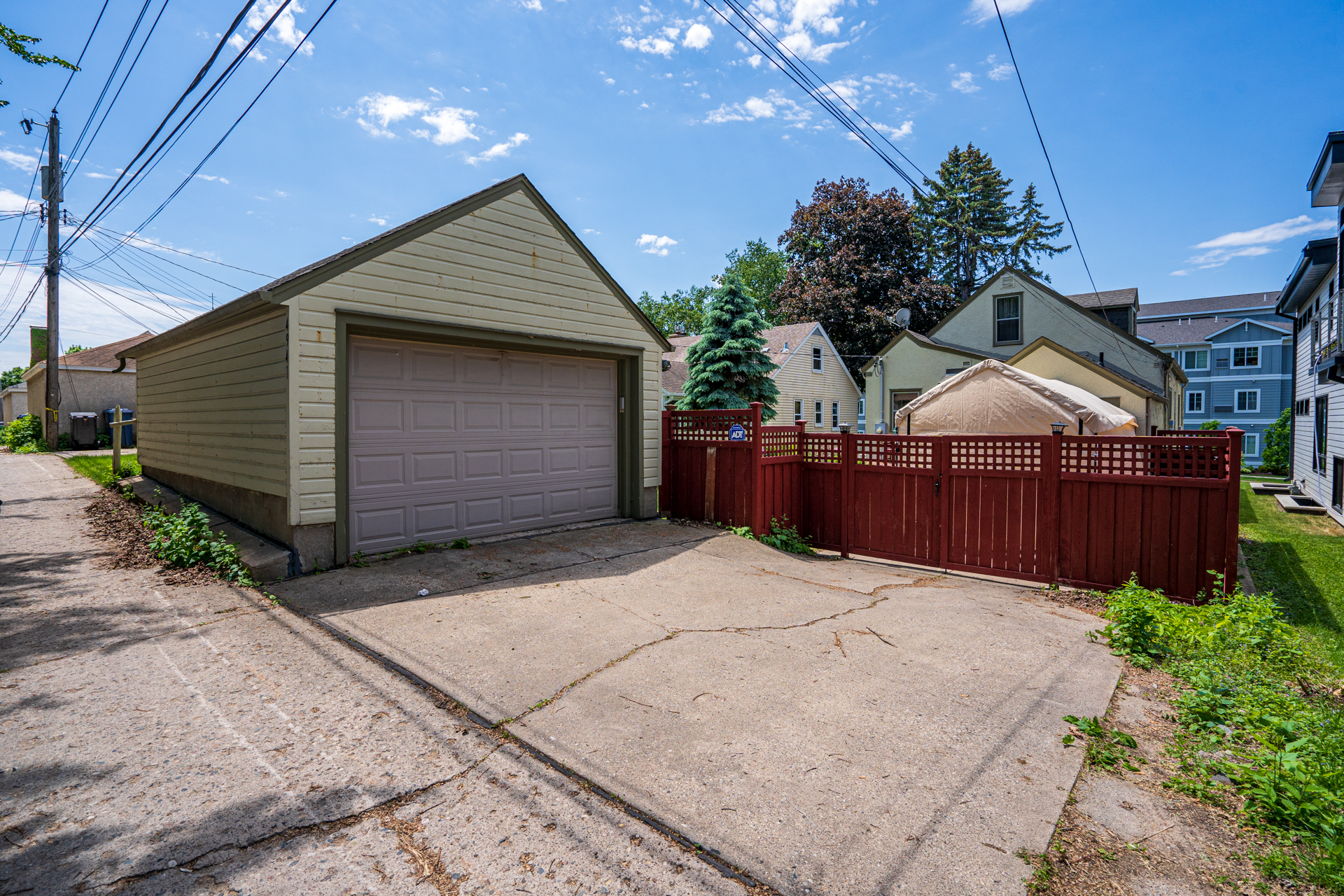 A peaceful residential alley featuring a green garage and enclosed backyard.