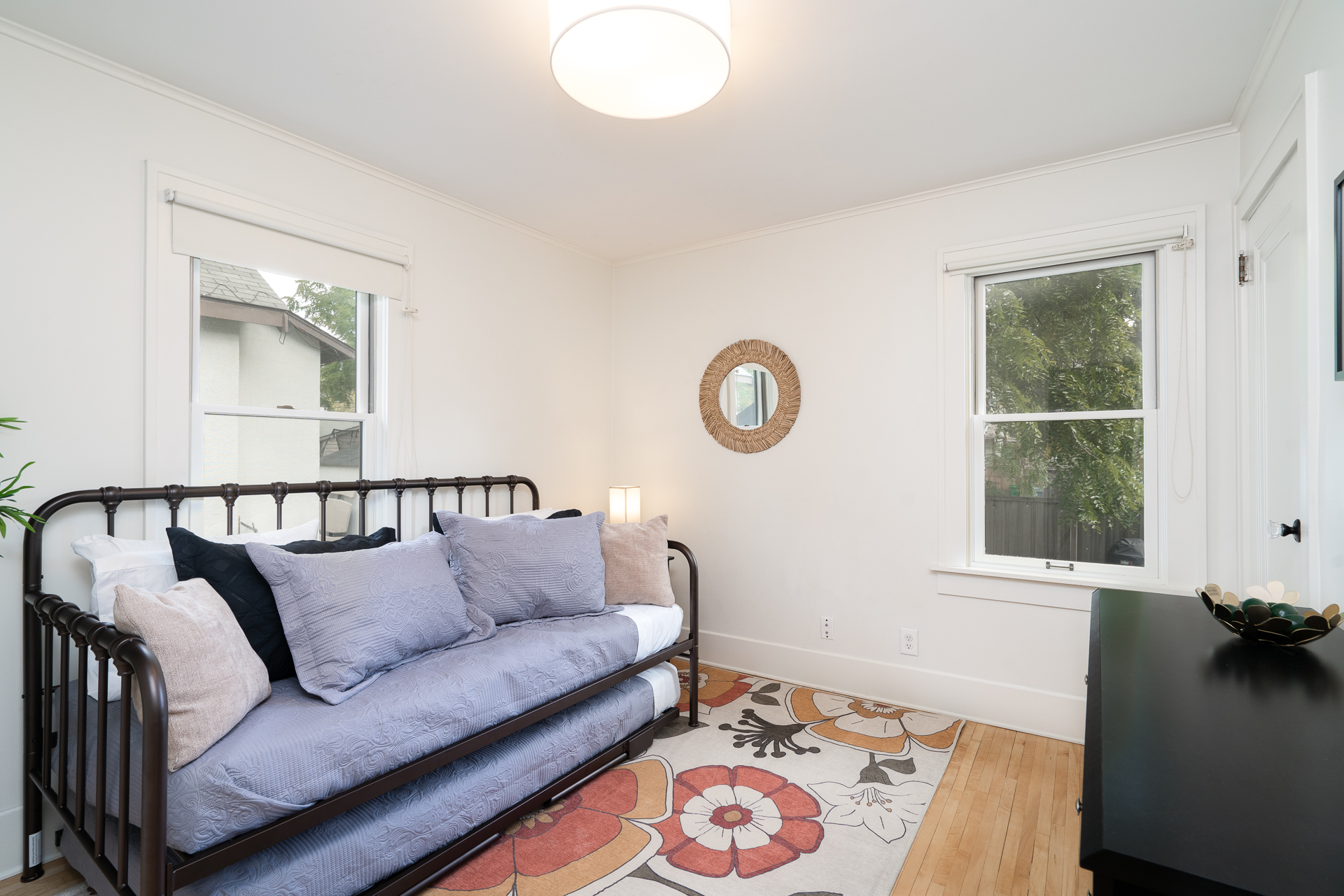 Cozy and stylish bedroom featuring a daybed, floral rug, and natural light.