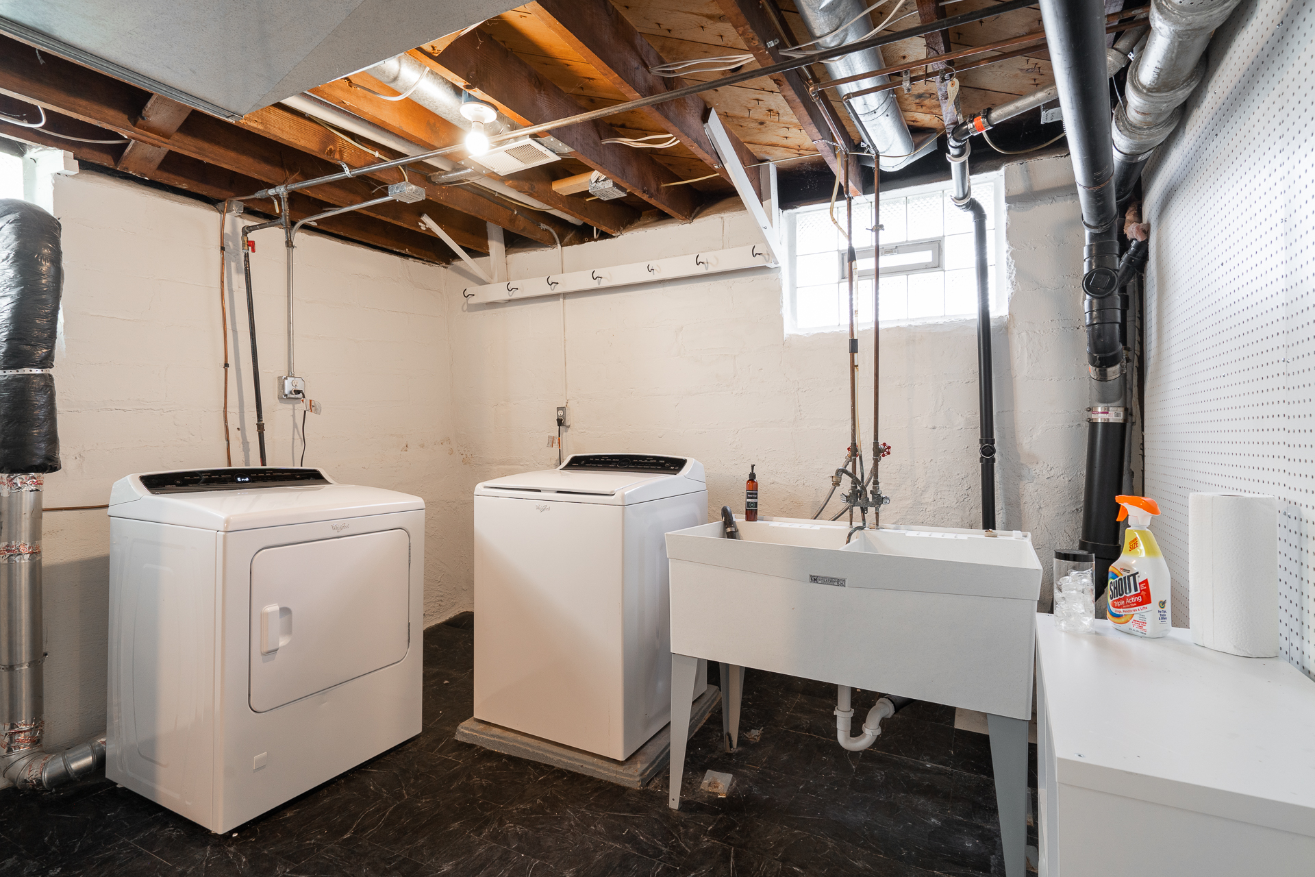 A tidy basement laundry room with modern appliances and a utility sink.