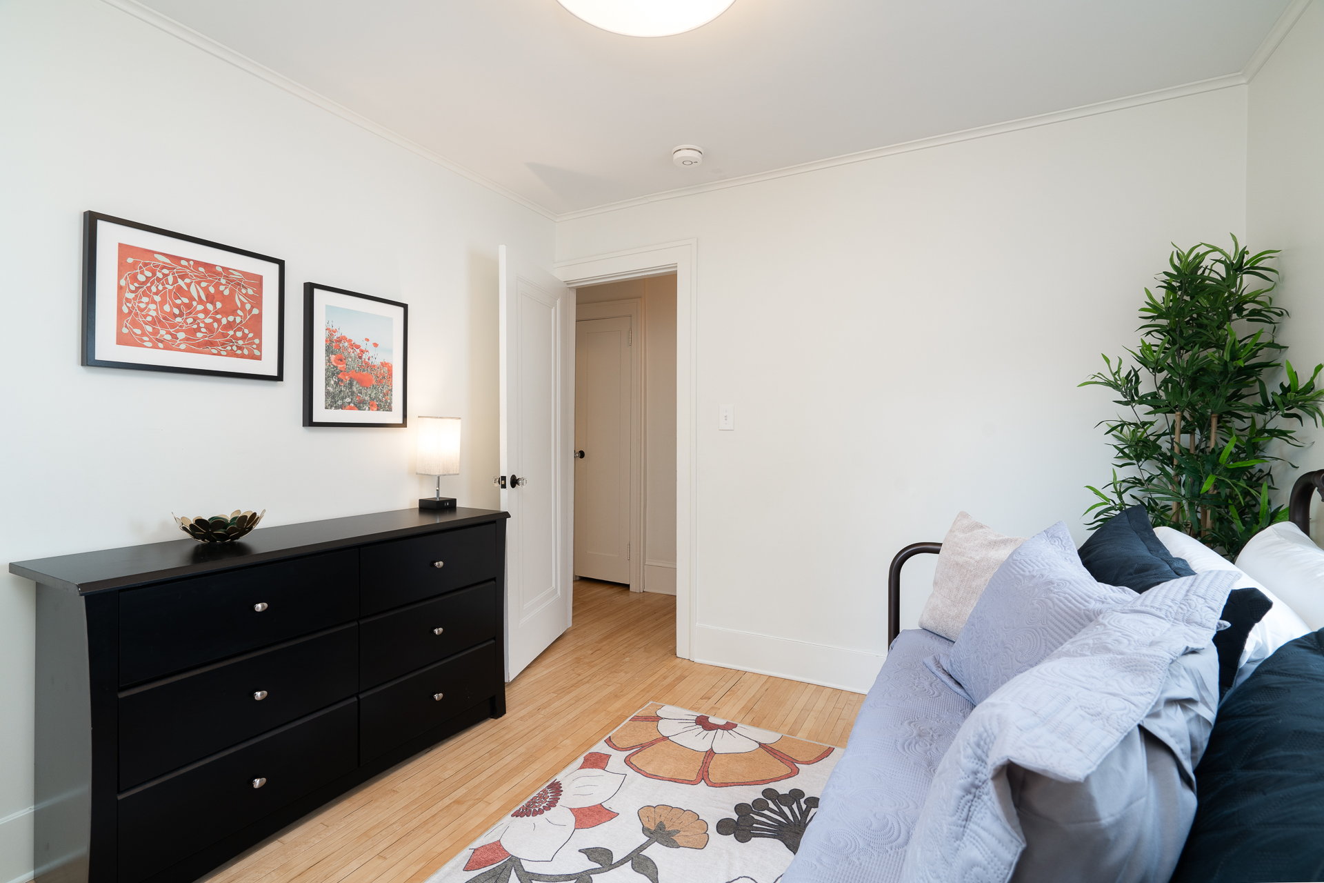 A cozy modern bedroom featuring a black dresser, framed art, and a stylish bed.