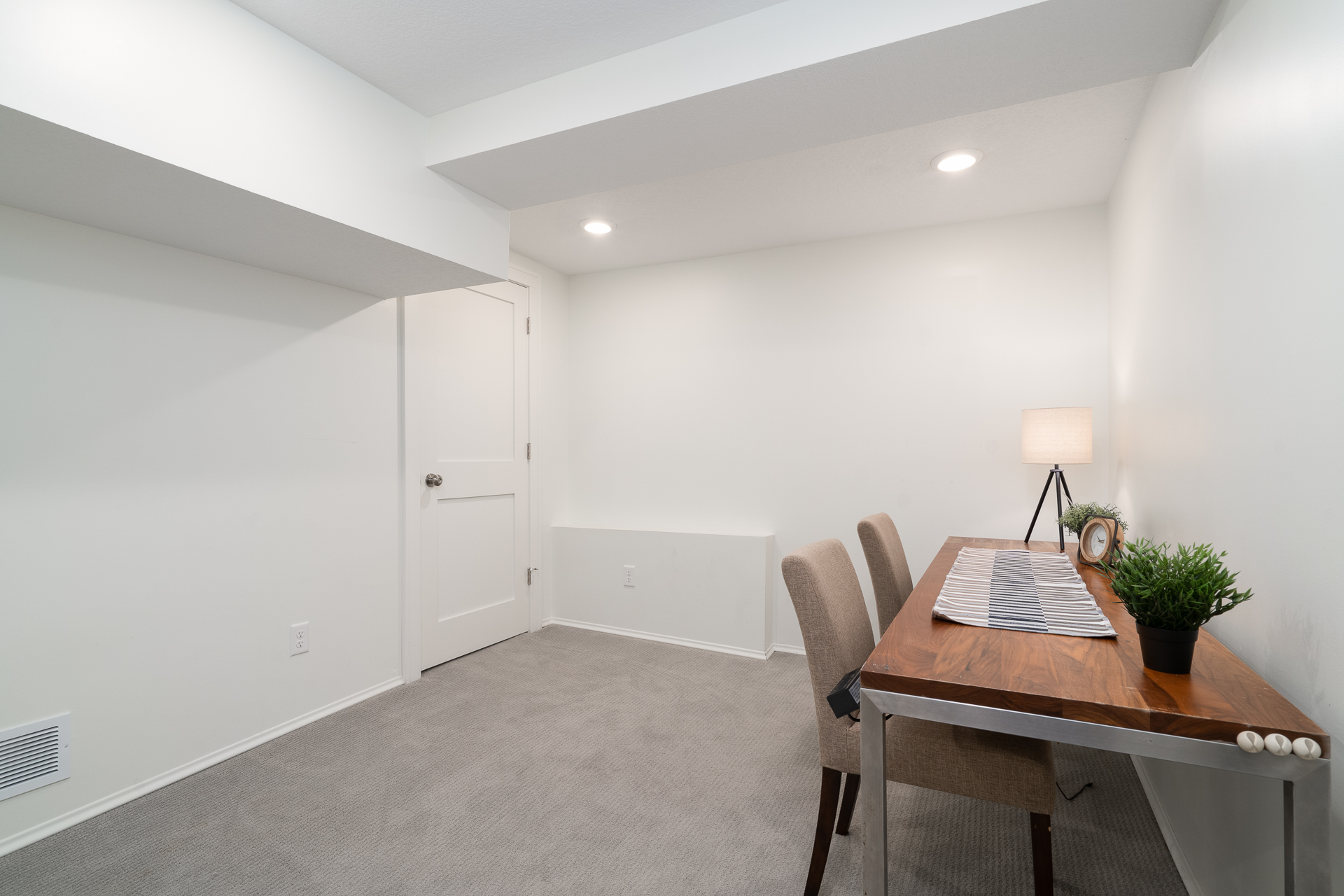 A cozy minimalist workspace featuring a wooden desk and beige chairs.