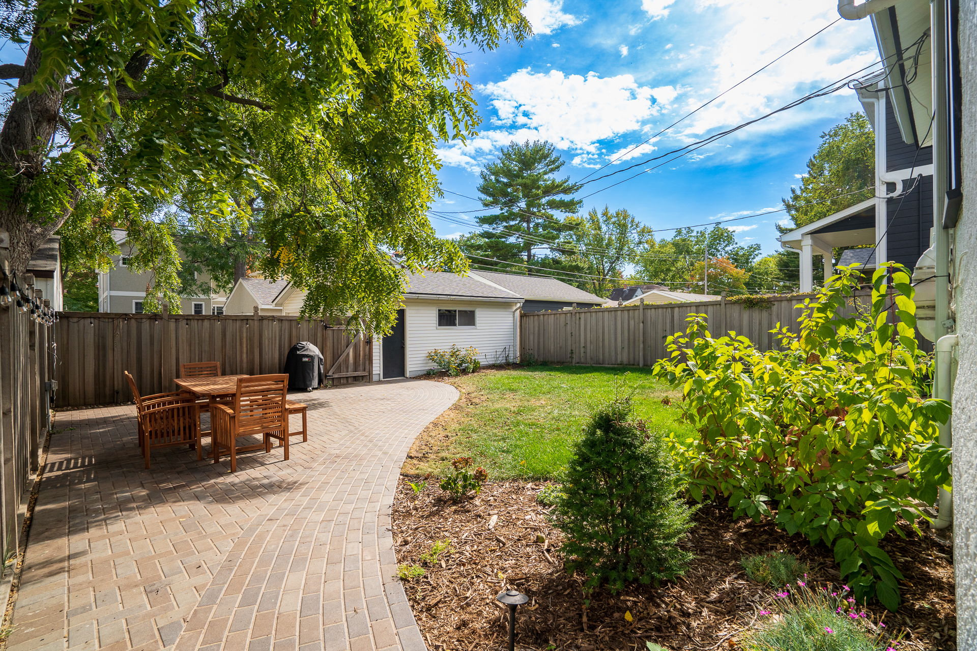 A serene backyard with a cozy dining area and lush greenery.