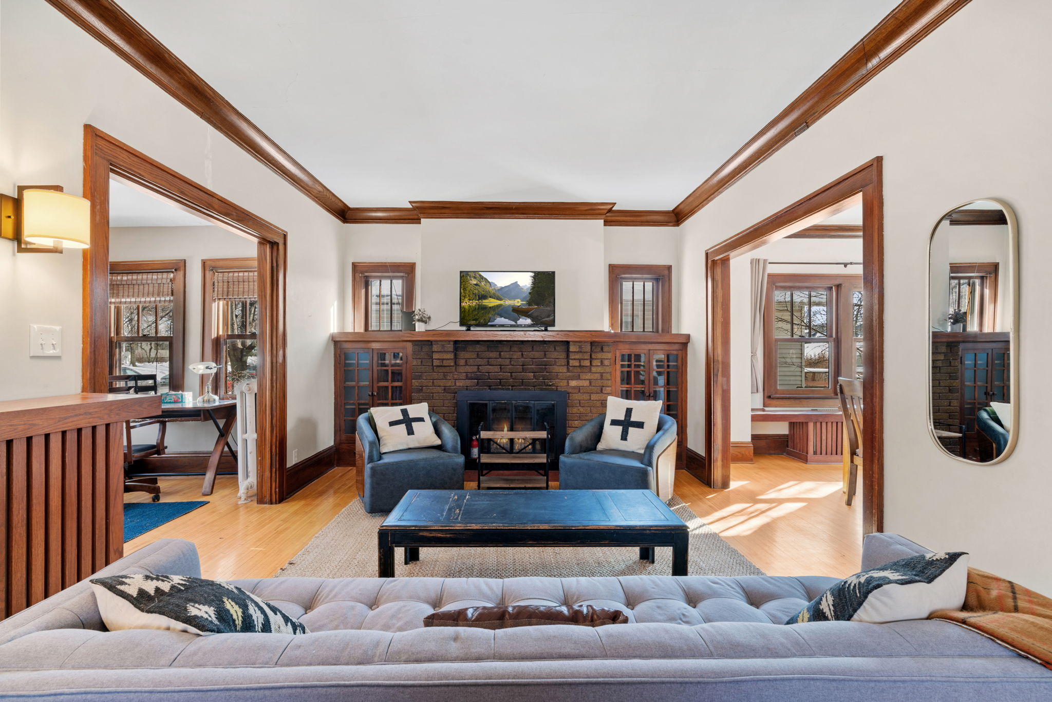 Cozy living room with a brick fireplace, blue armchairs, and a tufted sofa.