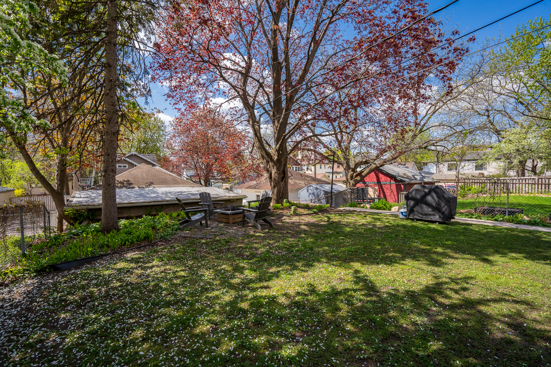 A tranquil spring backyard with inviting seating, vibrant trees, and a clear blue sky.
