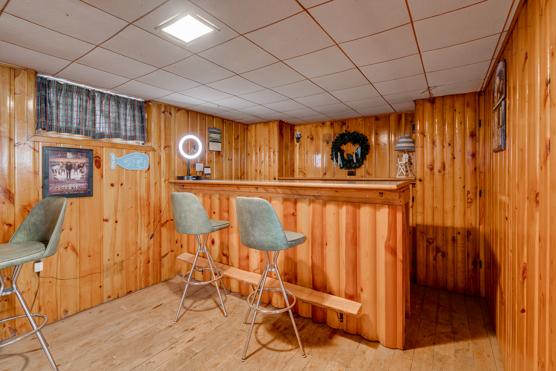 Cozy basement bar area with rustic wood paneling and modern seating.