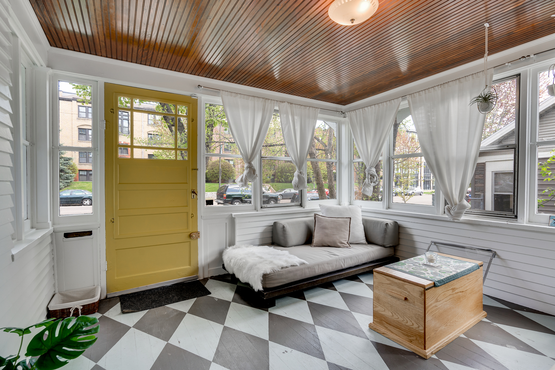 A bright and cozy sunroom featuring a yellow door and patterned floor.