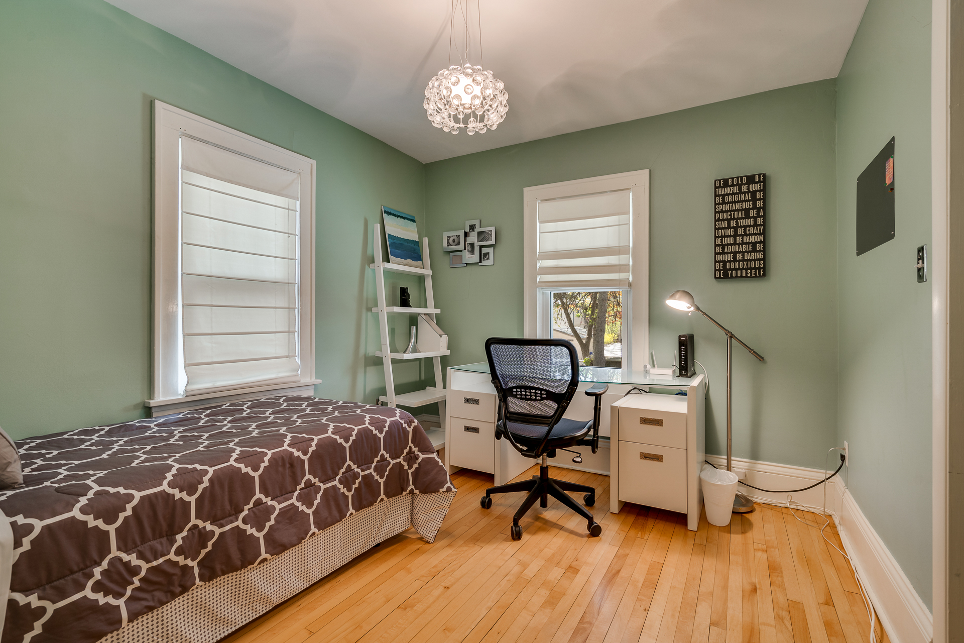 A modern, tranquil bedroom with a twin bed and a workspace.