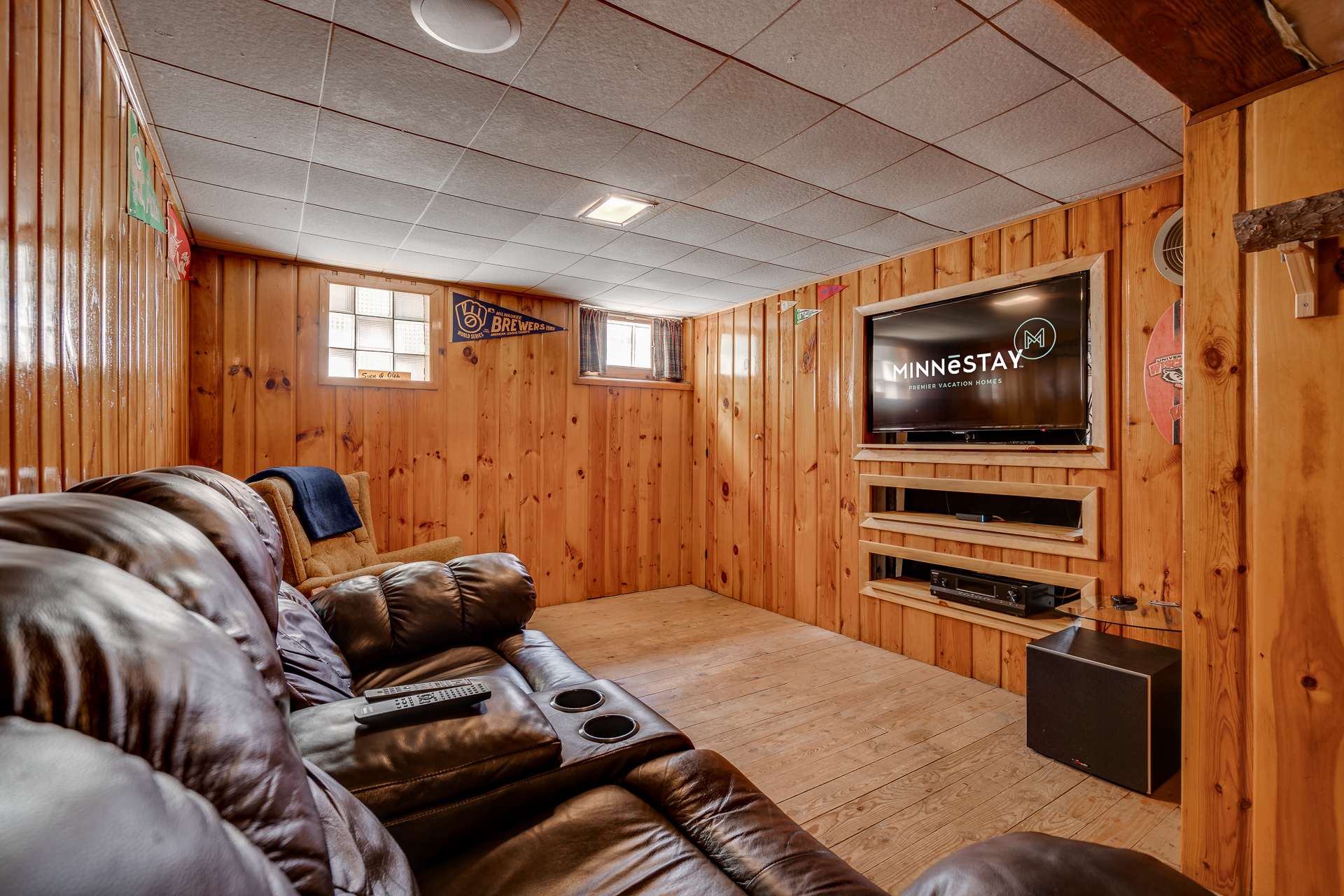 A cozy basement entertainment area with wooden walls and plush seating.
