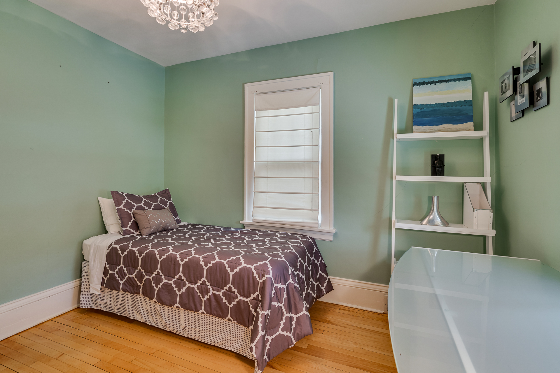 A cozy mint-green bedroom featuring a single bed and modern decor.