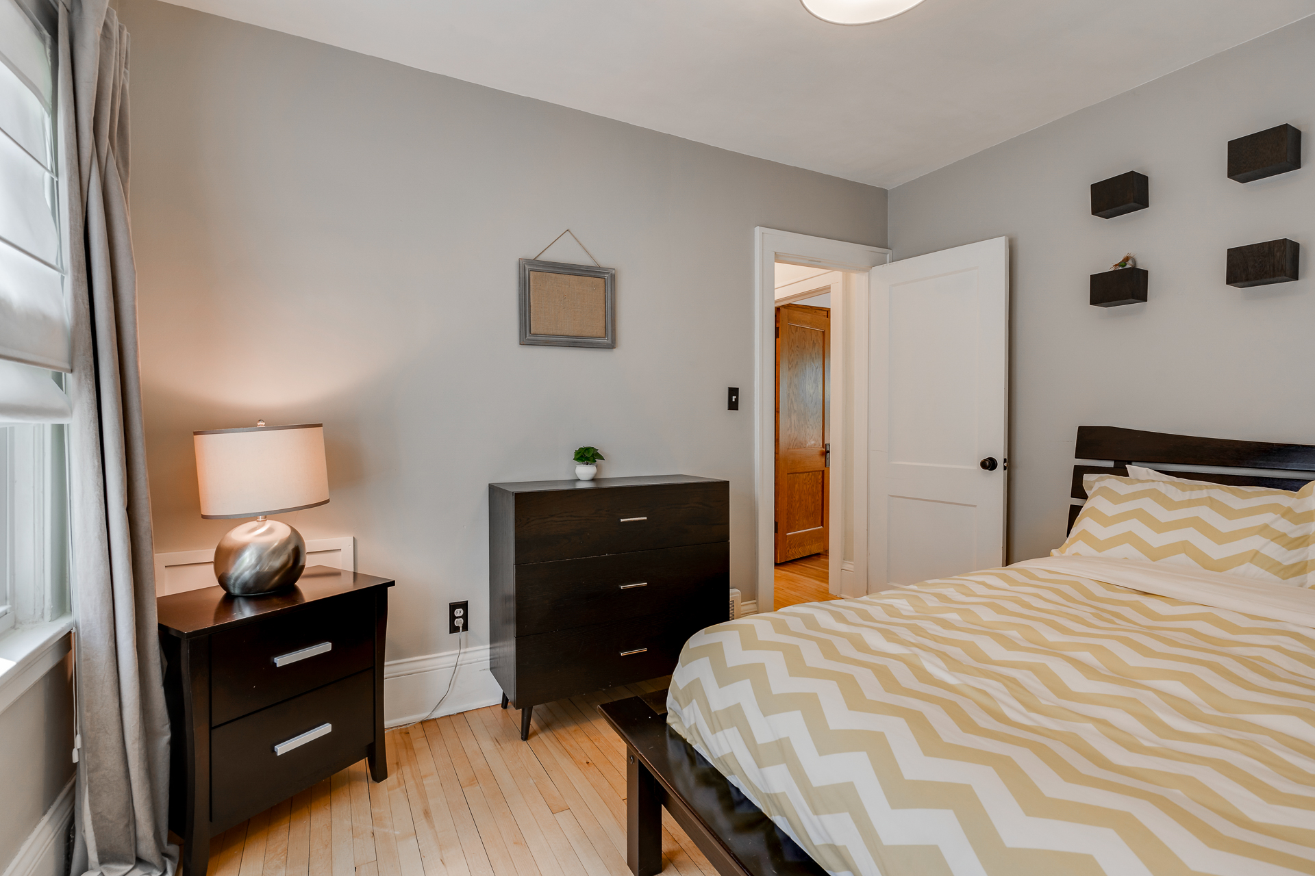A bright and cozy bedroom featuring modern decor and a zigzag-patterned bedspread.