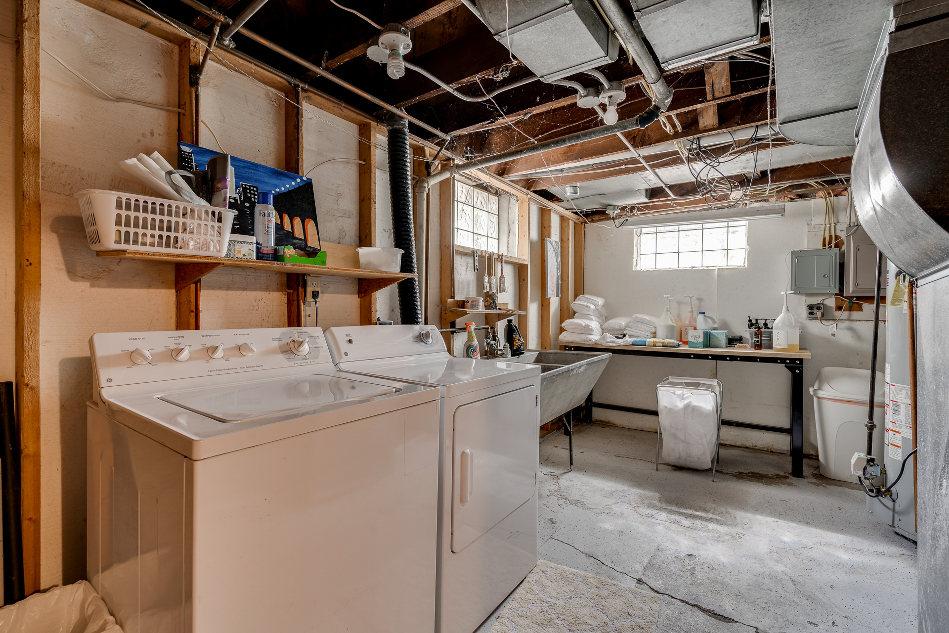 A functional basement laundry room with appliances and storage.