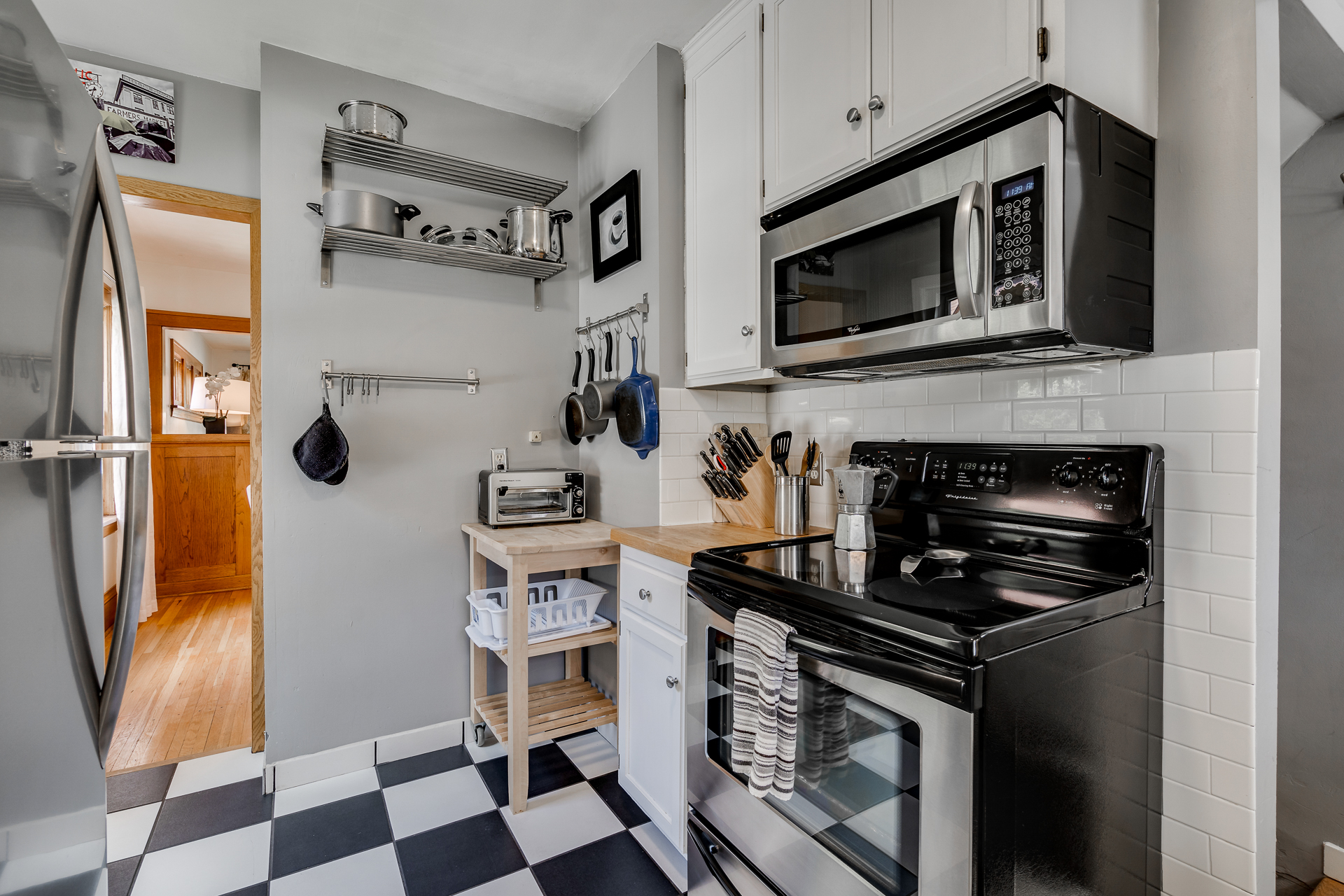 A modern kitchen with gray walls, white cabinets, and a stylish black and white checkered floor.