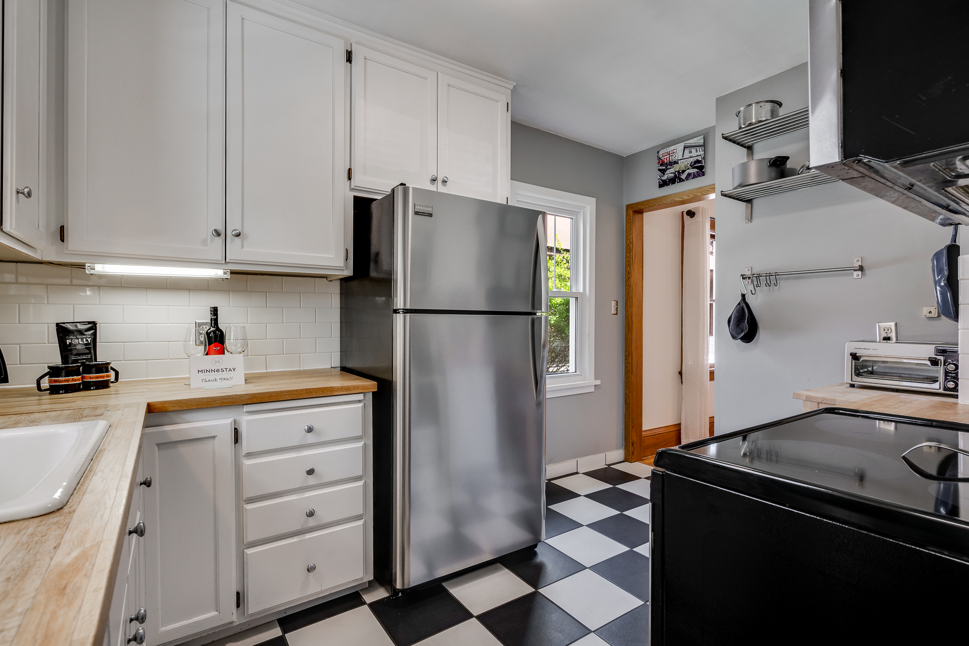 A stylish and modern kitchen with classic touches, featuring white cabinets and a checkerboard floor.