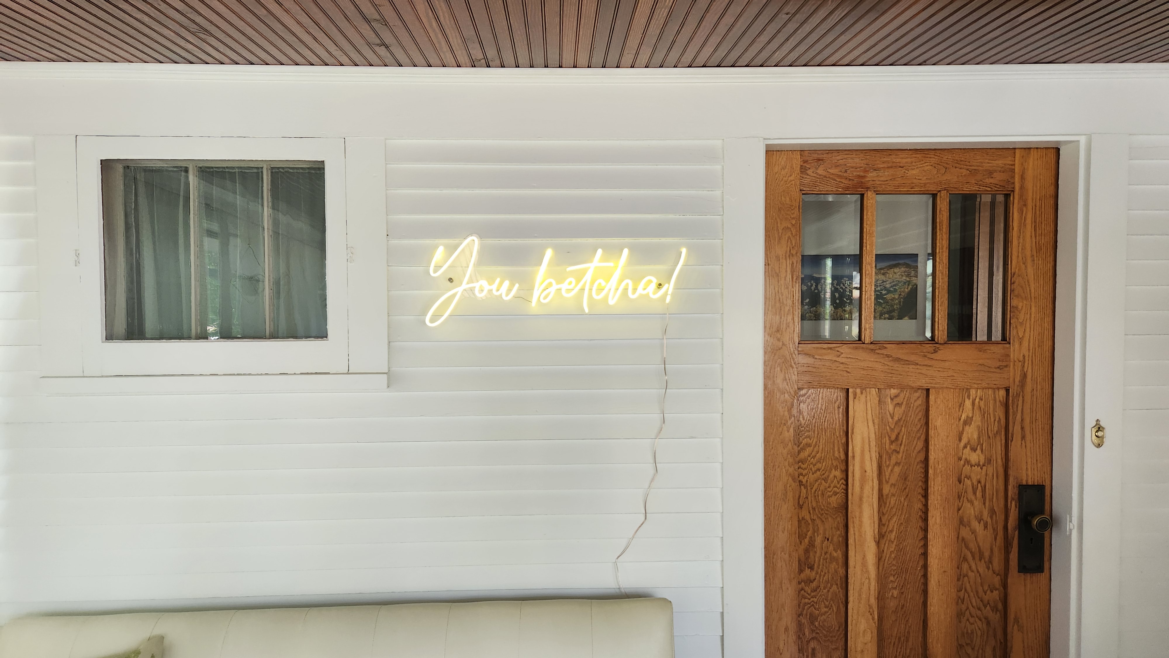 A cozy entryway featuring a glowing neon sign that says 'You betcha!'